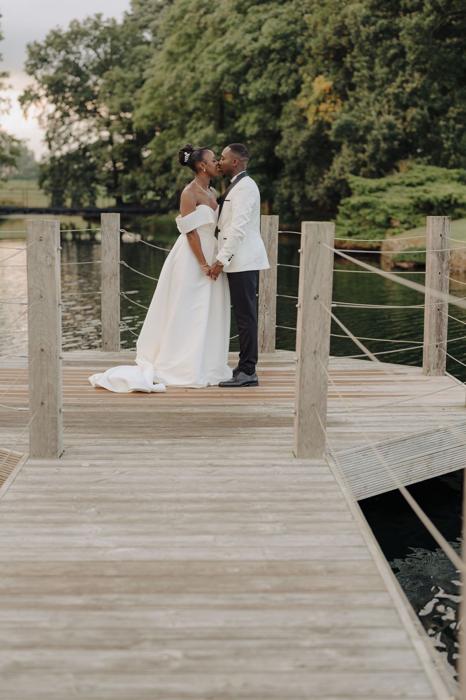 A romantic wedding moment captured on a wooden dock overlooking a peaceful lake.
