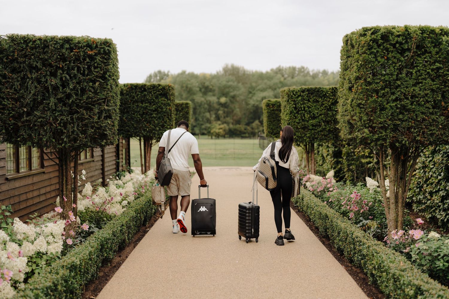 Garden pathway lined with hedges leading to wedding venue entrance.