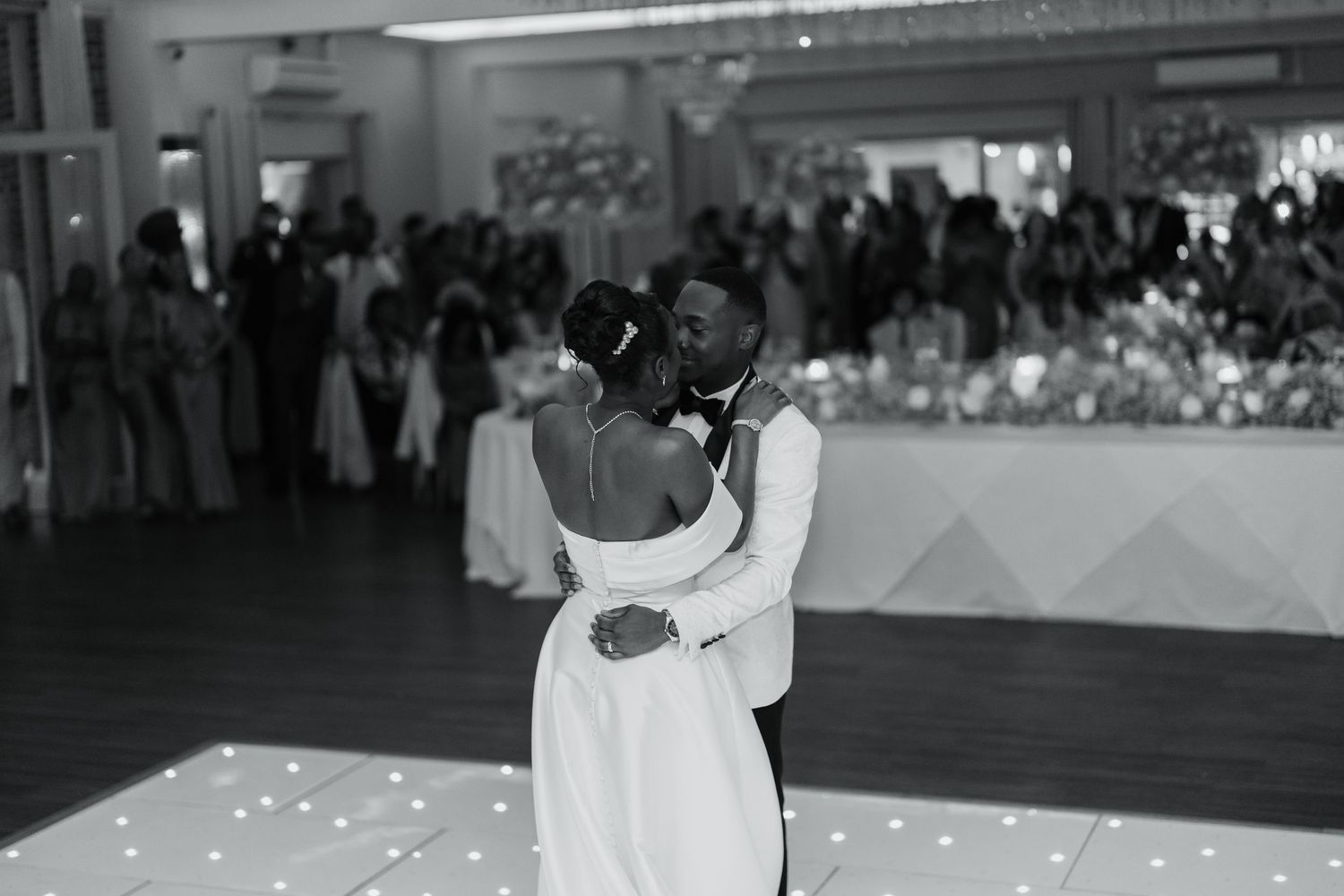 Wedding couple sharing first dance surrounded by guests at reception.