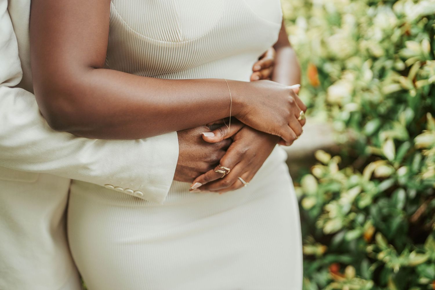 Close-up detail of hands resting against a cream-colored dress.