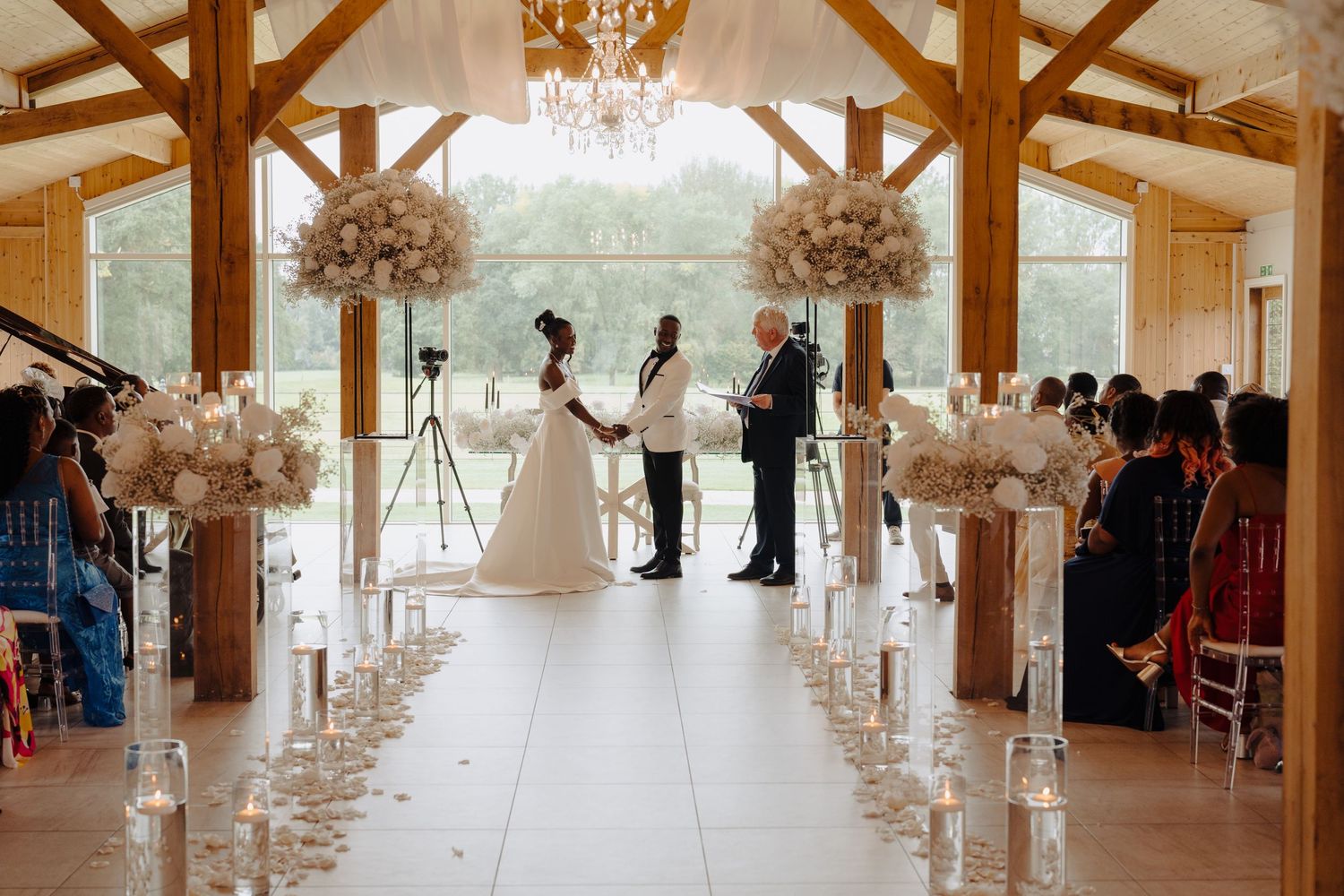 Elegant wedding venue with wooden beams, crystal chandeliers and white floral arrangements creates a romantic atmosphere.