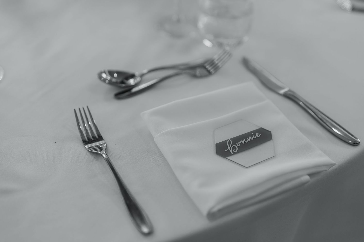 Clean white place settings with silverware arranged on a formal dining table.