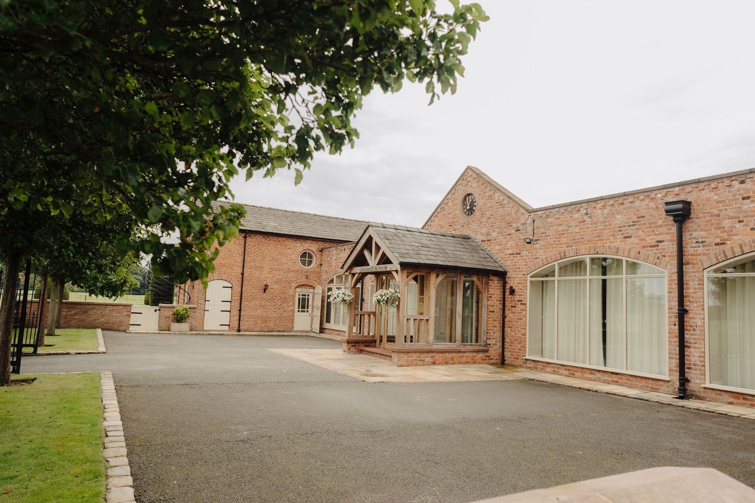 Exterior view of a brick wedding venue building with modern architectural details and a paved driveway.