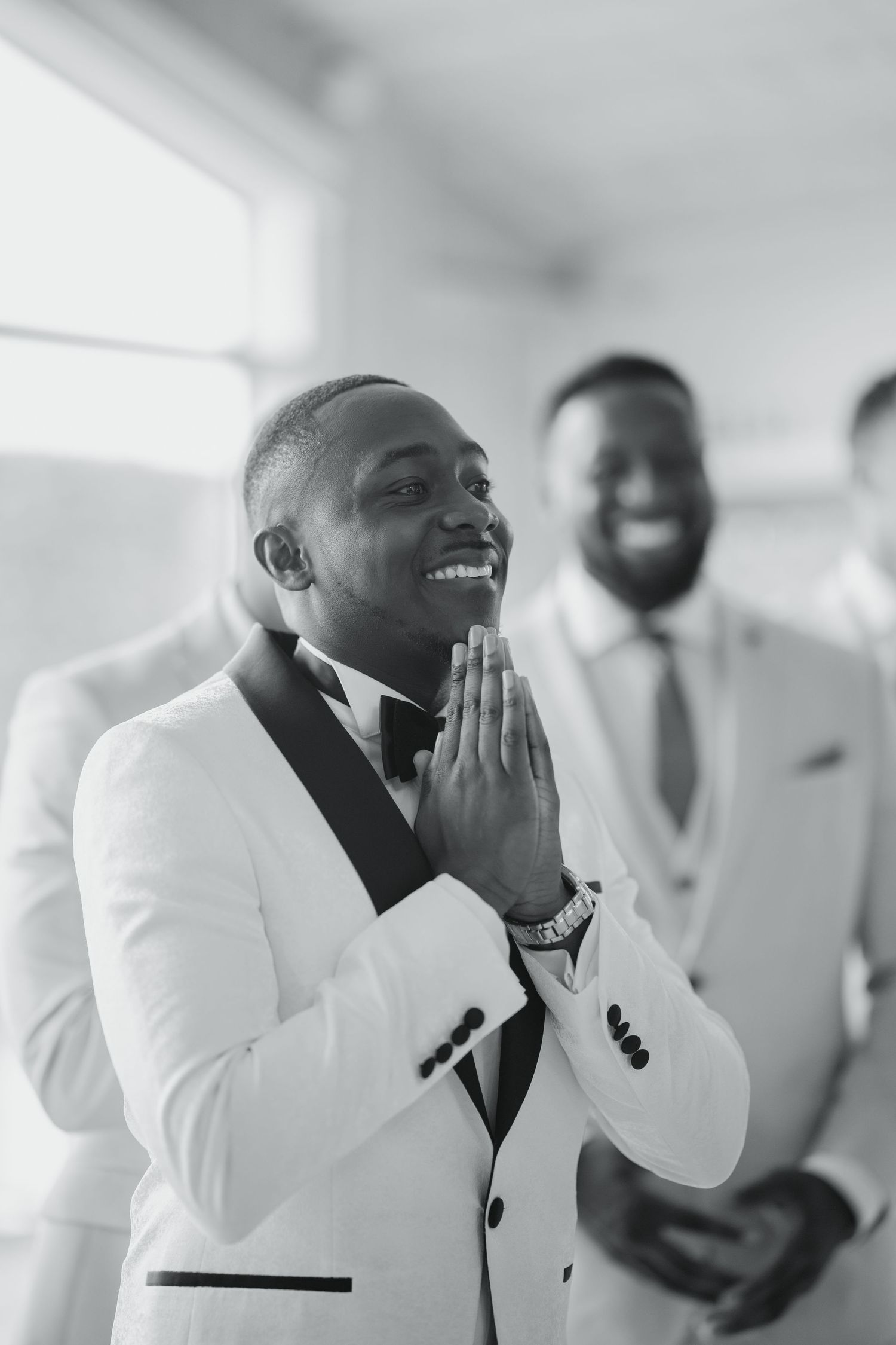 Wedding party members in crisp white tuxedos express joy and excitement before the ceremony.