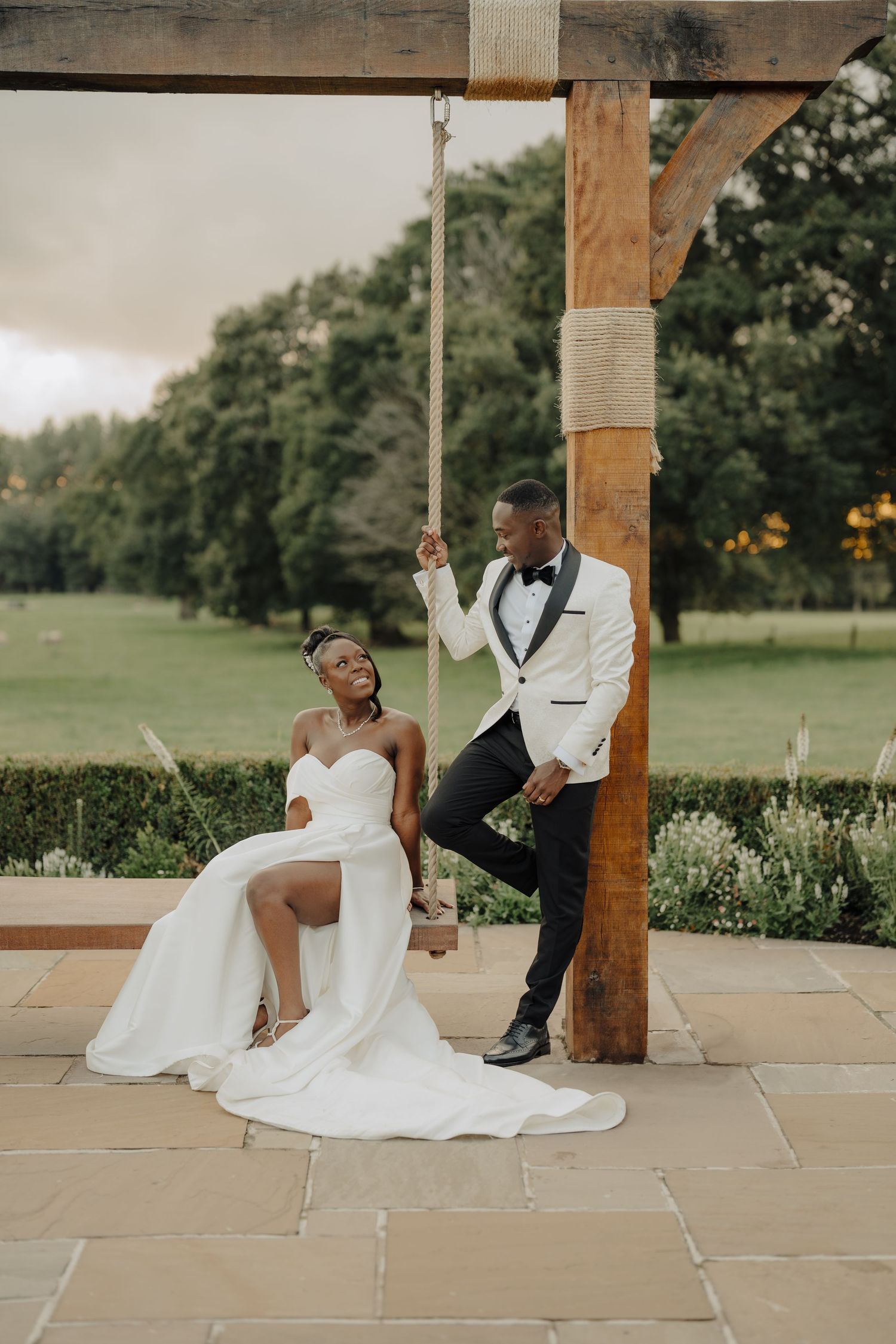 Elegant wedding portraits under wooden beams on stone patio with garden views.