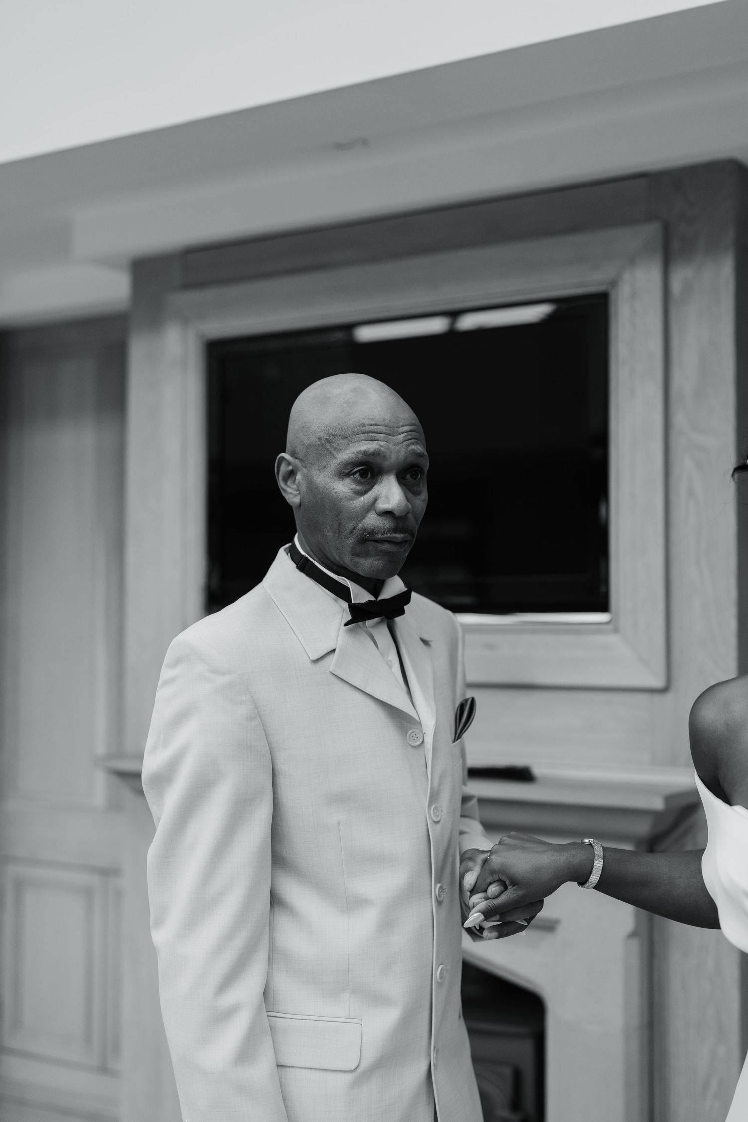Black and white portrait of someone in a crisp white suit jacket looking contemplative.