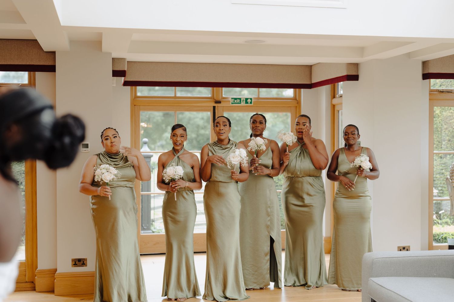 Wedding party posing together in a sunlit room with large windows.