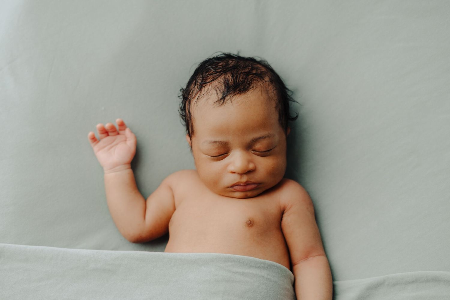 Sleeping newborn baby lies peacefully on soft white bedding.