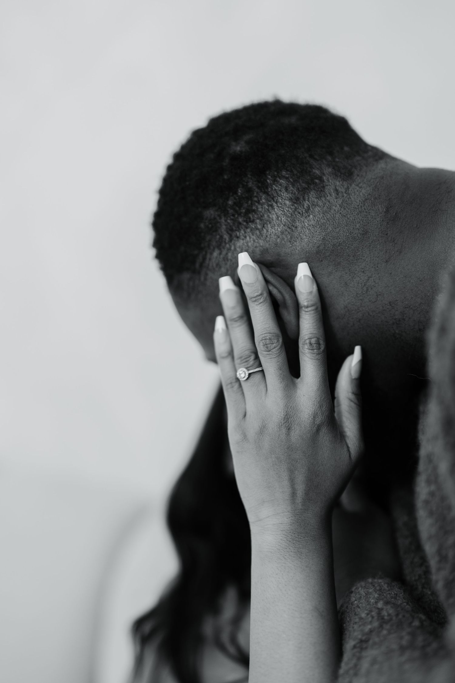 Close-up of hands tenderly touching against a monochrome background.