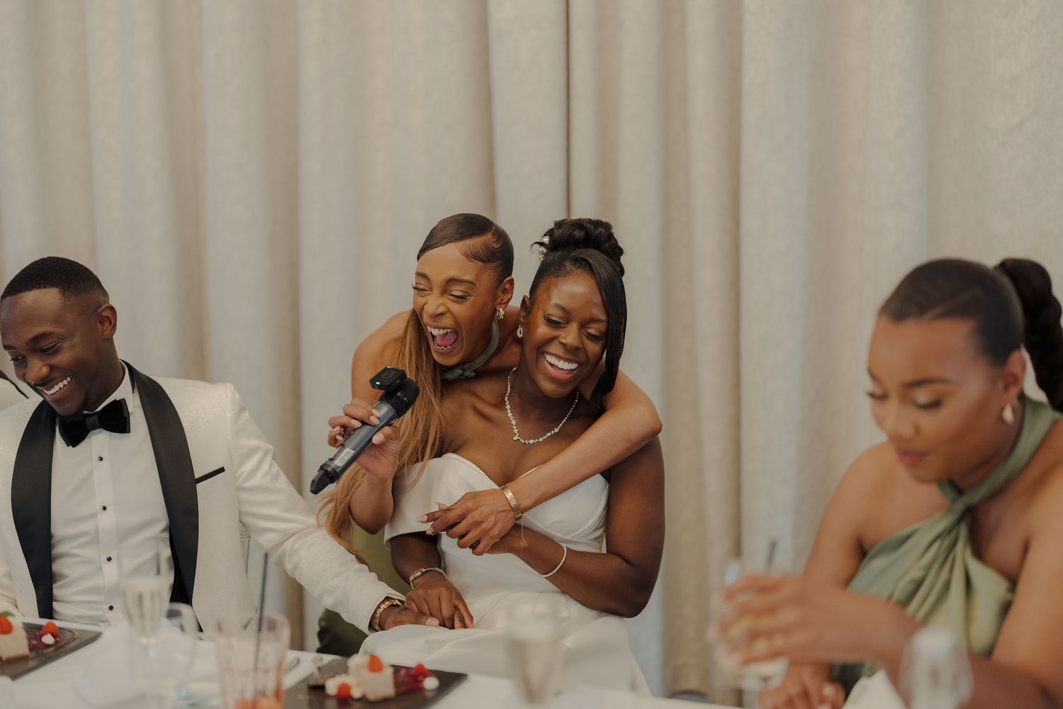 Wedding party guests laughing and celebrating together during a joyous reception moment.