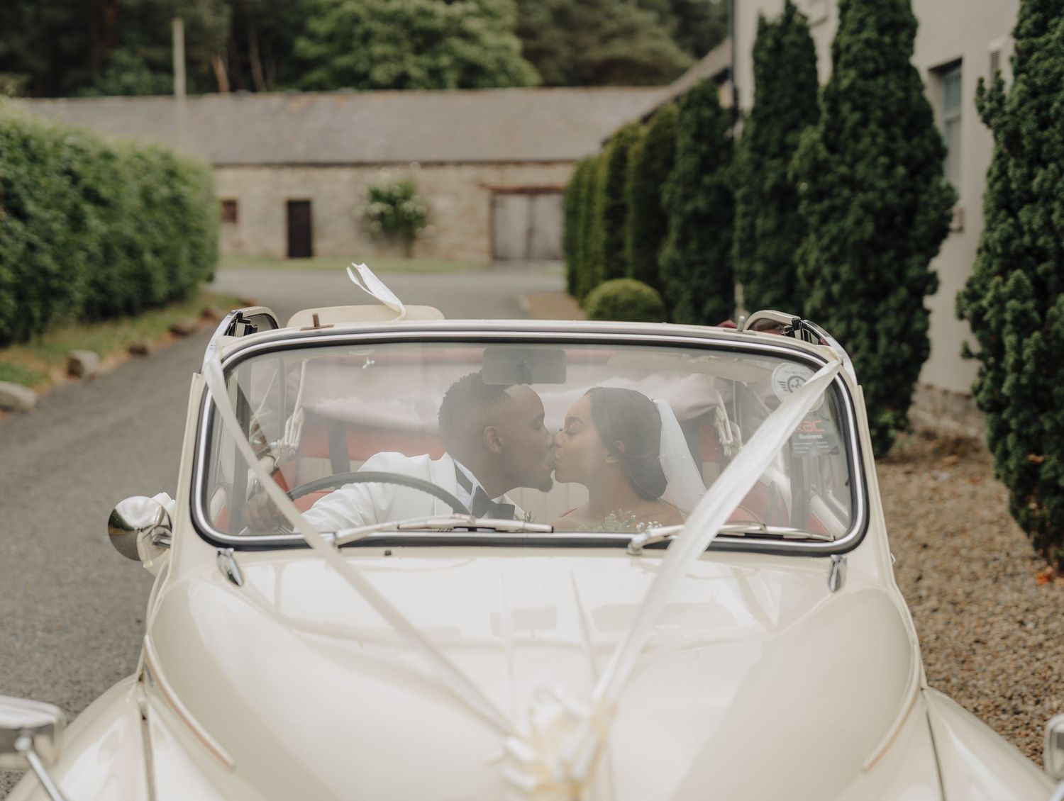 A classic white vintage wedding car parked outside during a celebration.