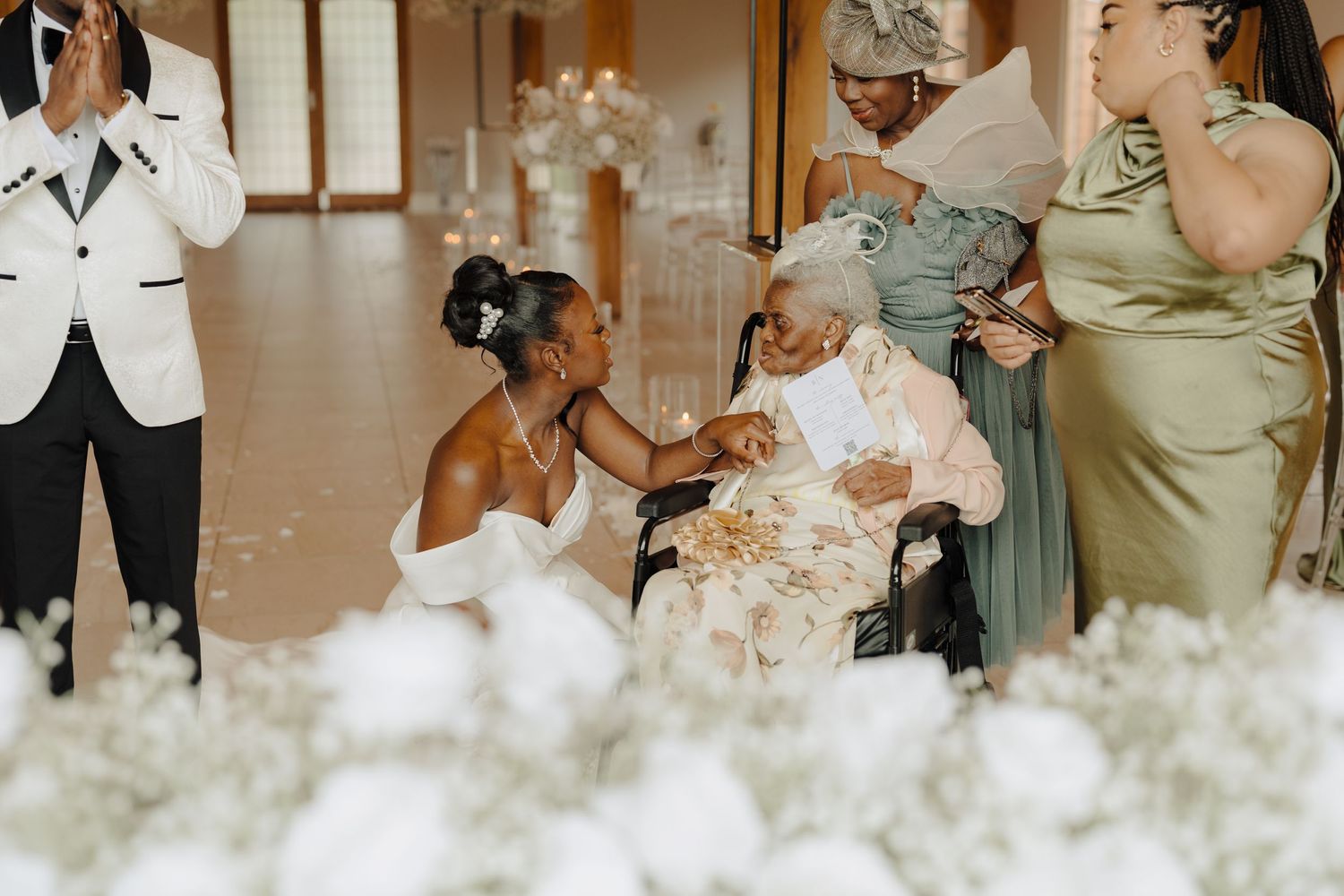 Wedding reception guests gather around decorative floral arrangements.