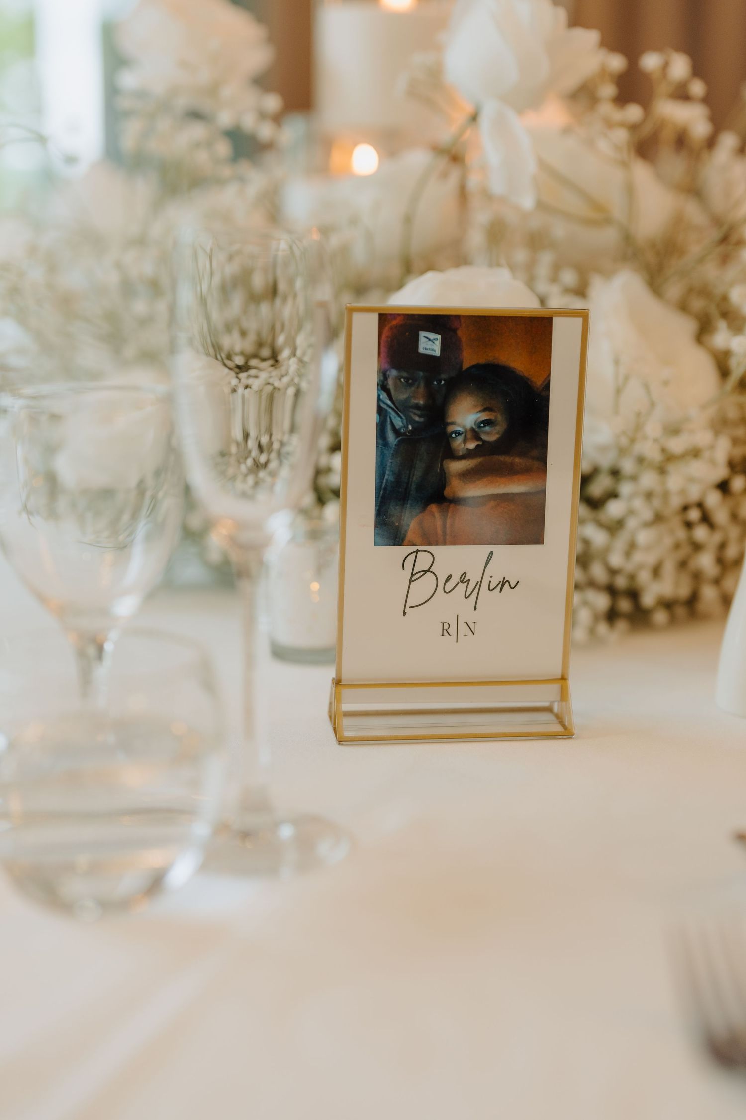 Elegant wedding reception table settings with floral decorations and name cards in gold frames.