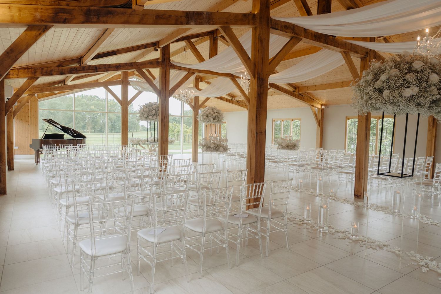 Rustic wooden barn venue set up for a wedding ceremony with white chairs and decorative draping.