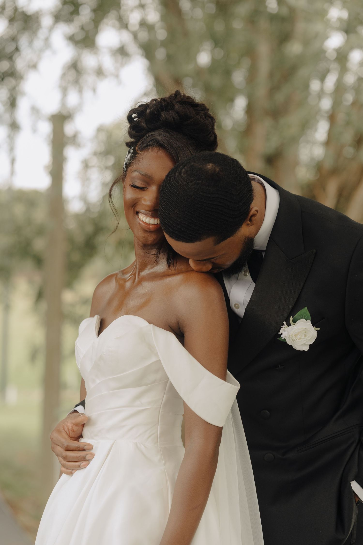 A romantic wedding moment captured in a wooded outdoor setting.