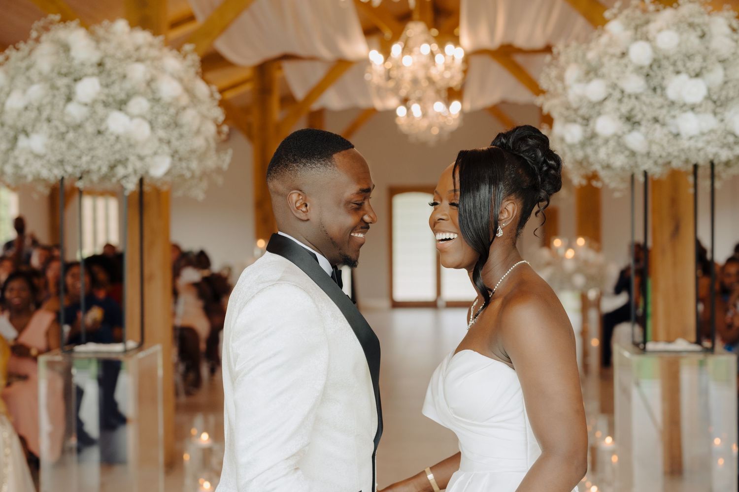 Elegant wedding venue decorated with white floral arrangements and crystal chandeliers.