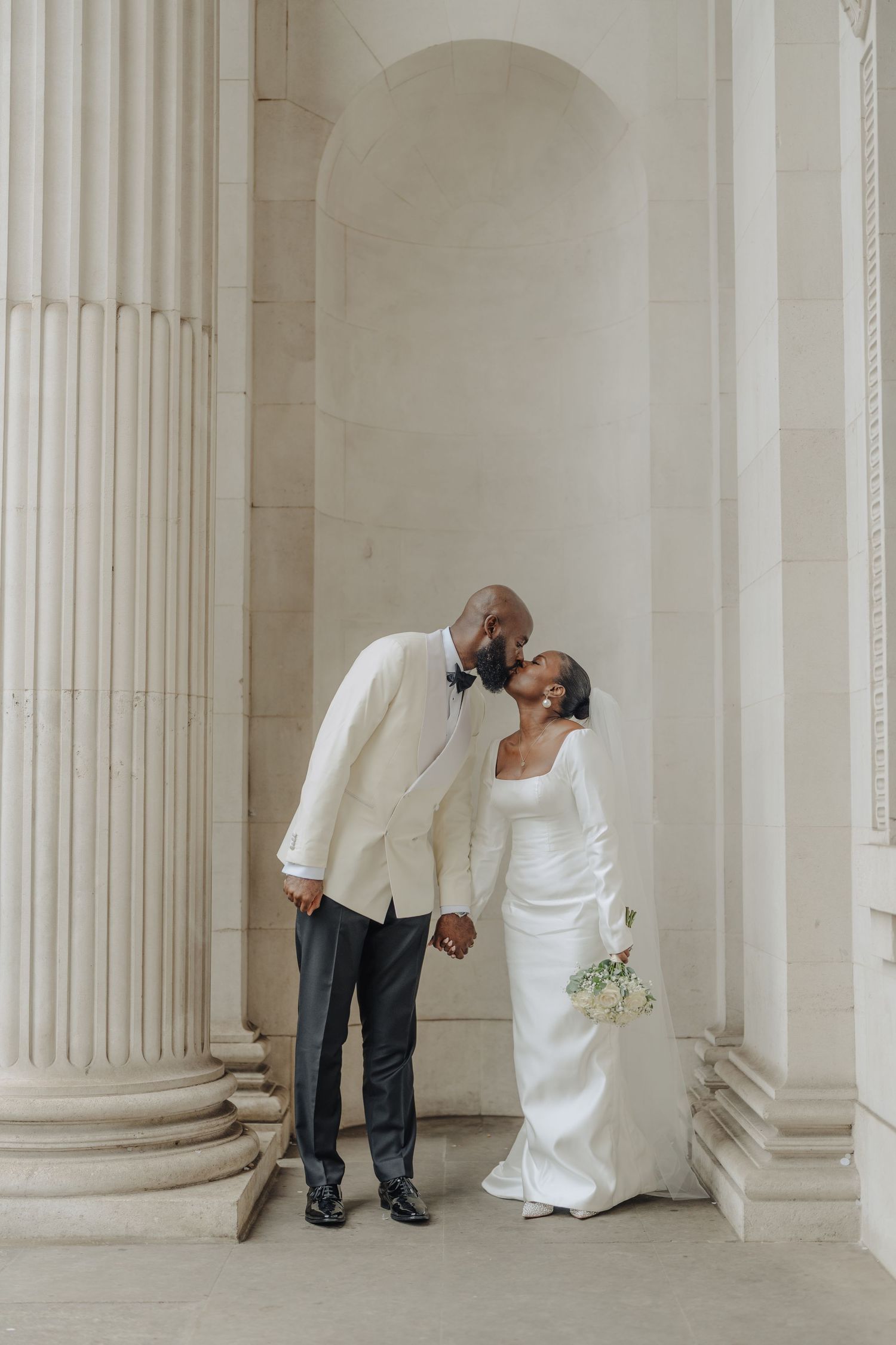 A romantic wedding photo series captured between classical white columns in an elegant setting.