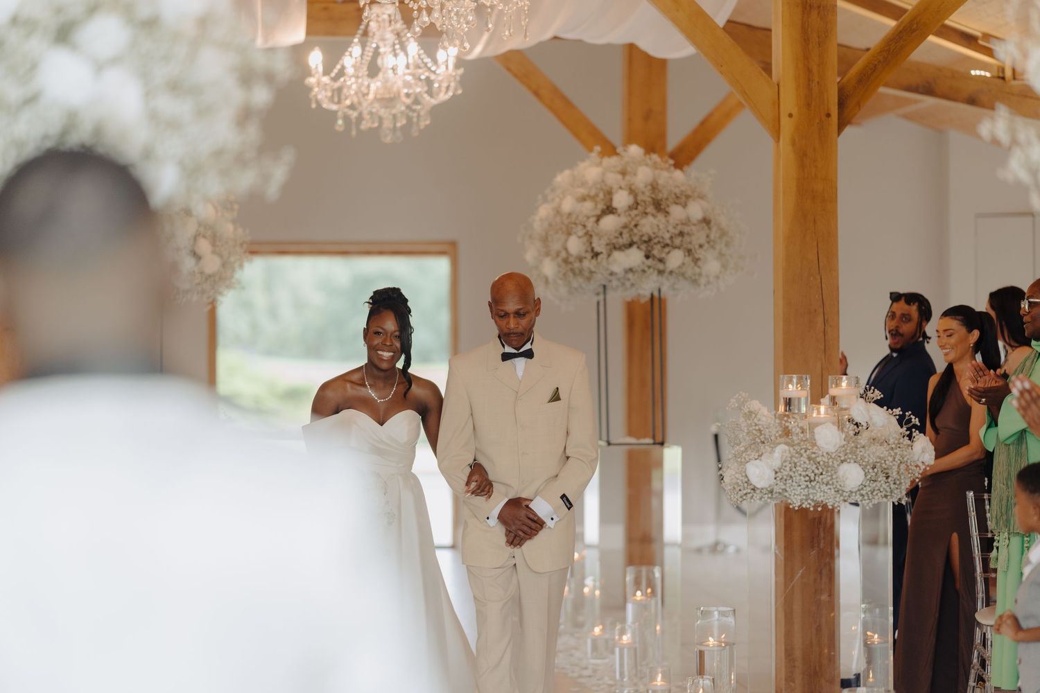 Wedding ceremony venue features rustic wooden beams and elegant crystal chandeliers.
