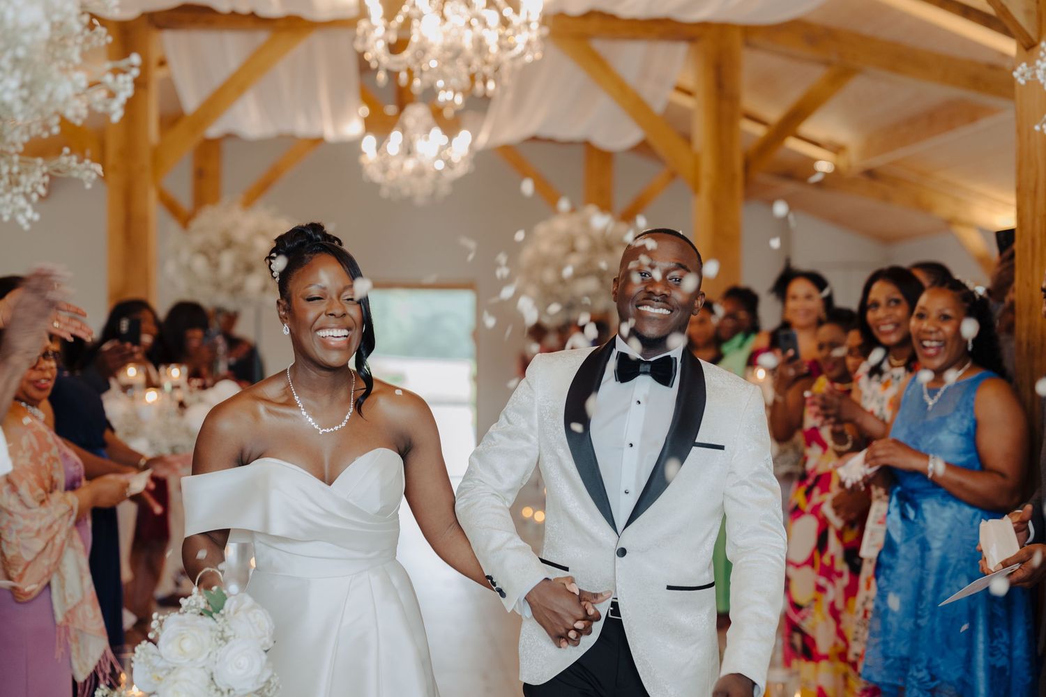 Wedding guests celebrate in a beautifully decorated venue with chandeliers and floral arrangements.