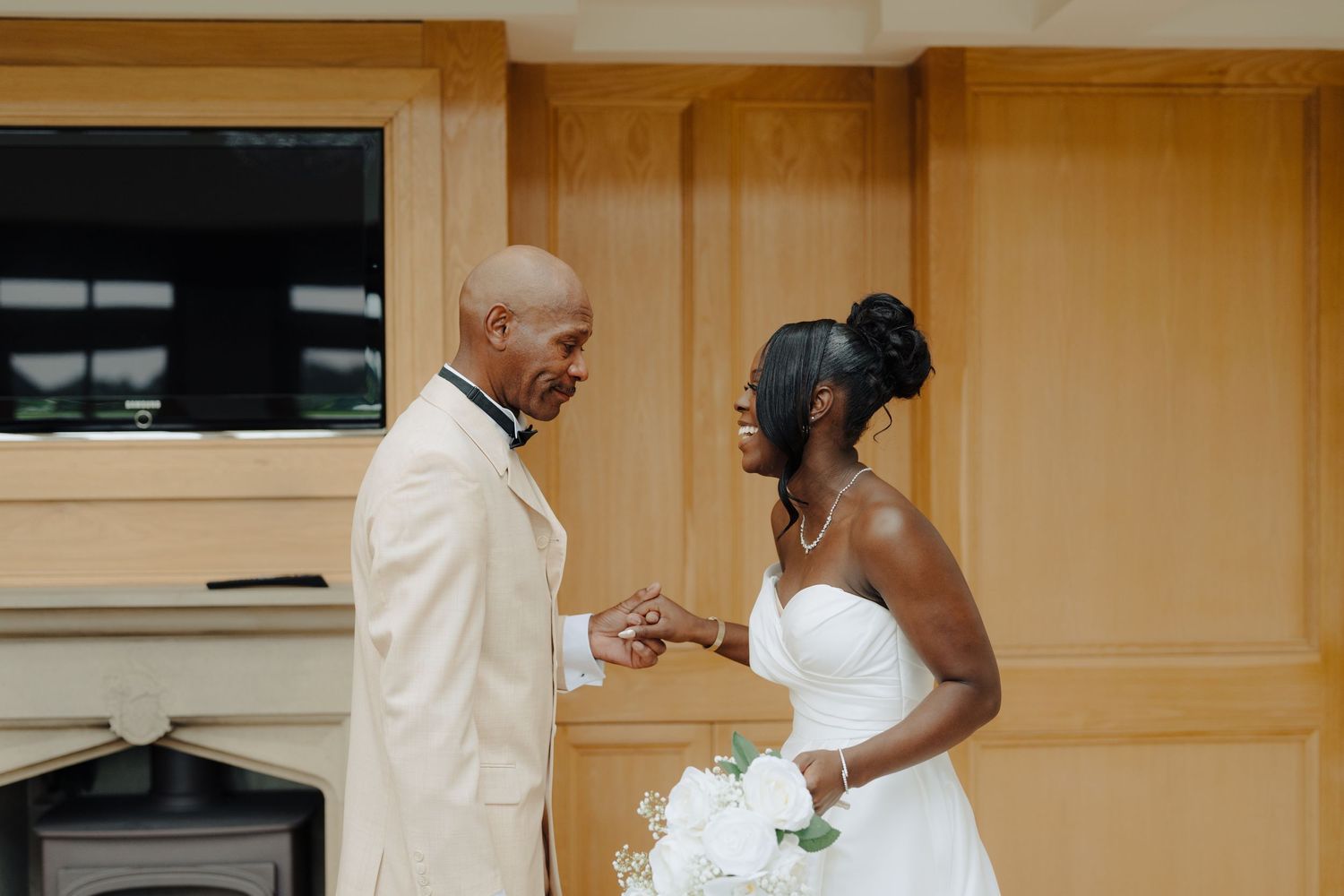 Wedding party members in elegant white attire share a touching moment together.