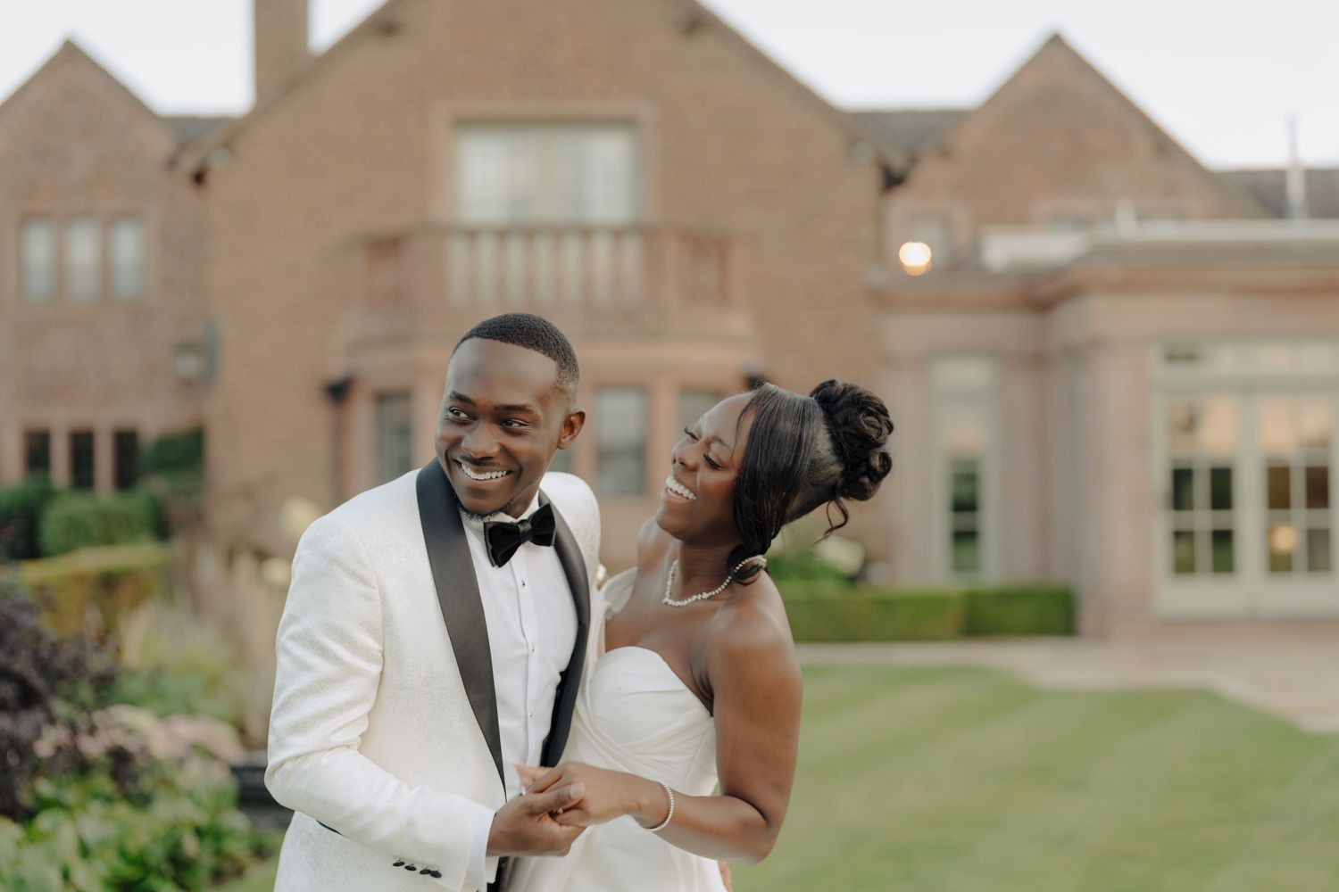 Wedding couple sharing romantic moments outside a grand brick building.
