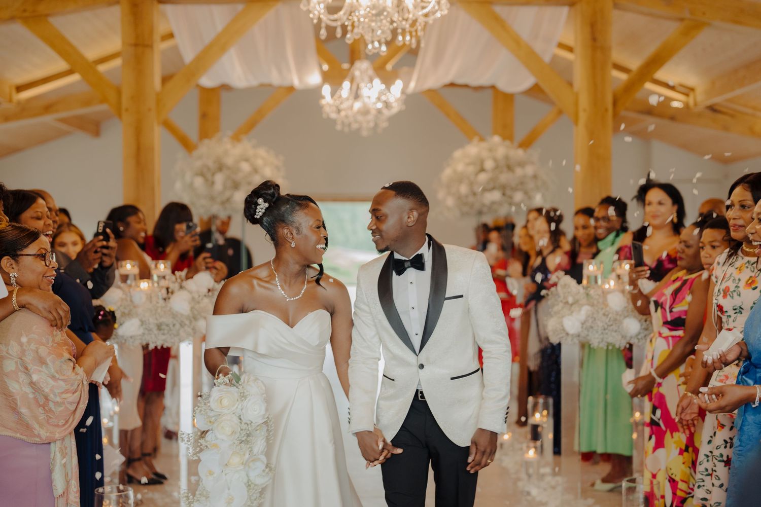 Wedding celebration in progress at an elegant venue with wooden beams and crystal lighting.