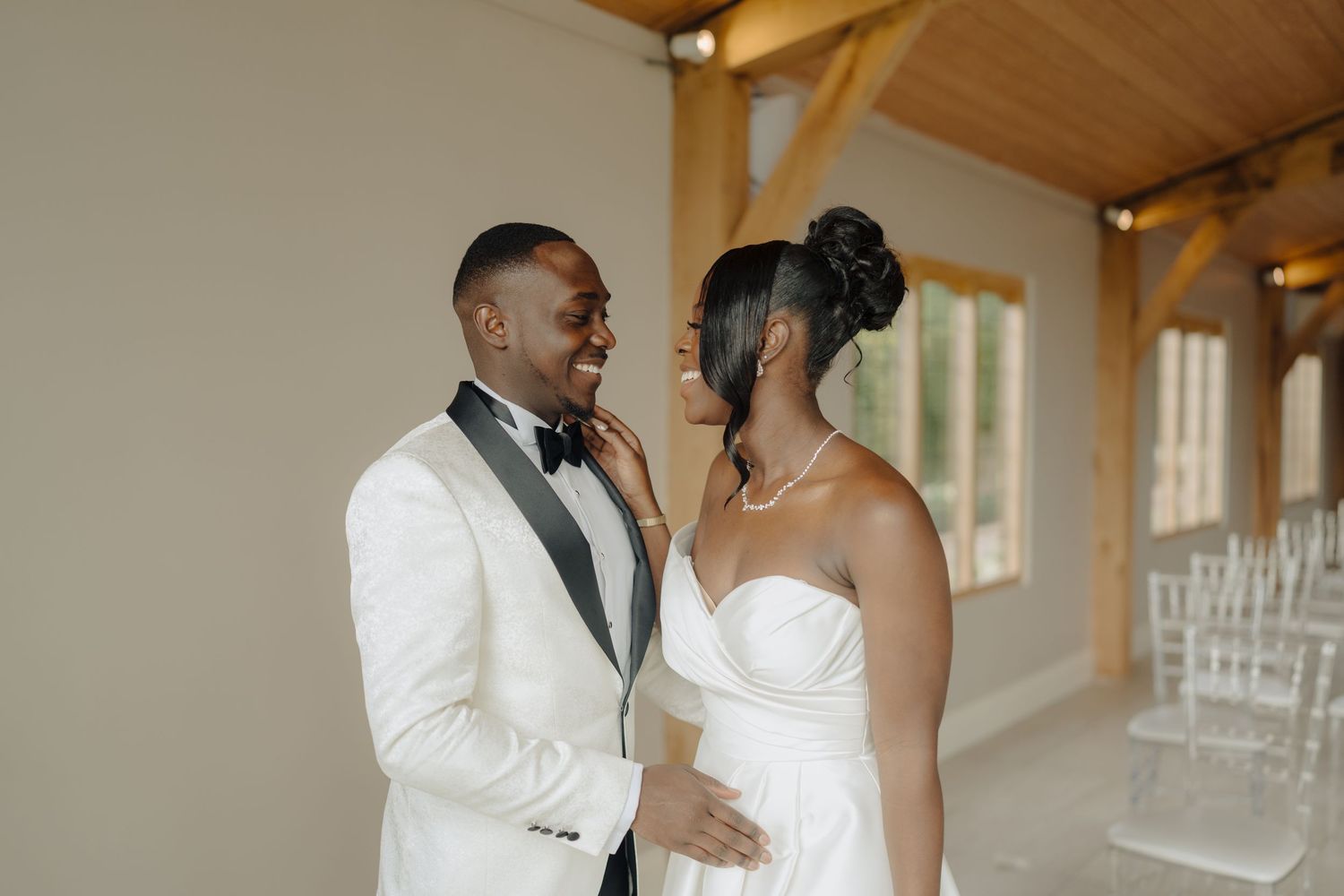 Newlyweds sharing tender moments in an indoor venue with wooden beams.