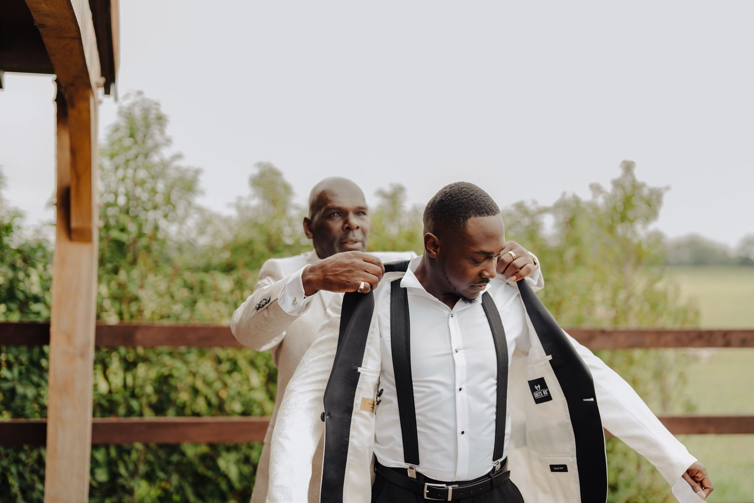 Wedding party members in formal attire standing on an outdoor wooden deck.