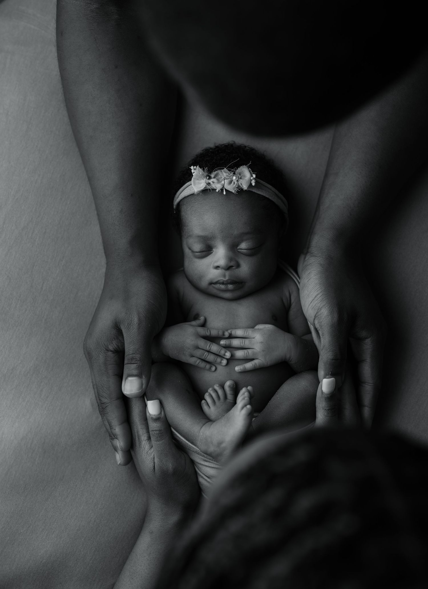 Black and white close-up photo series showing gentle hands cradling a newborn baby.
