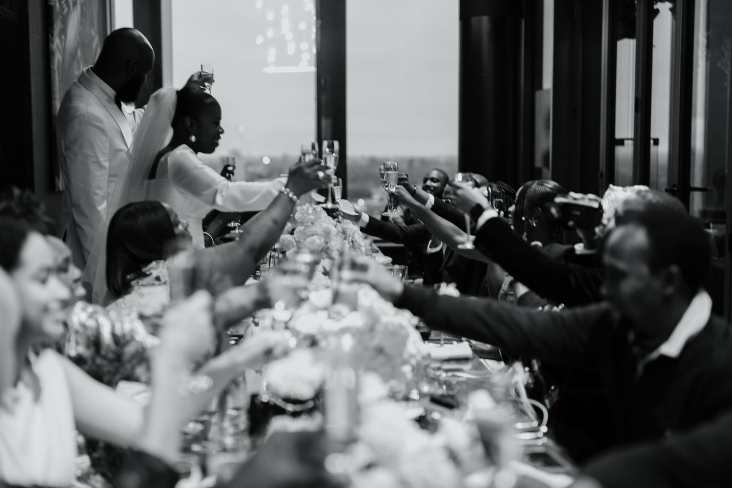 Black and white reception scene with guests celebrating at decorated tables.