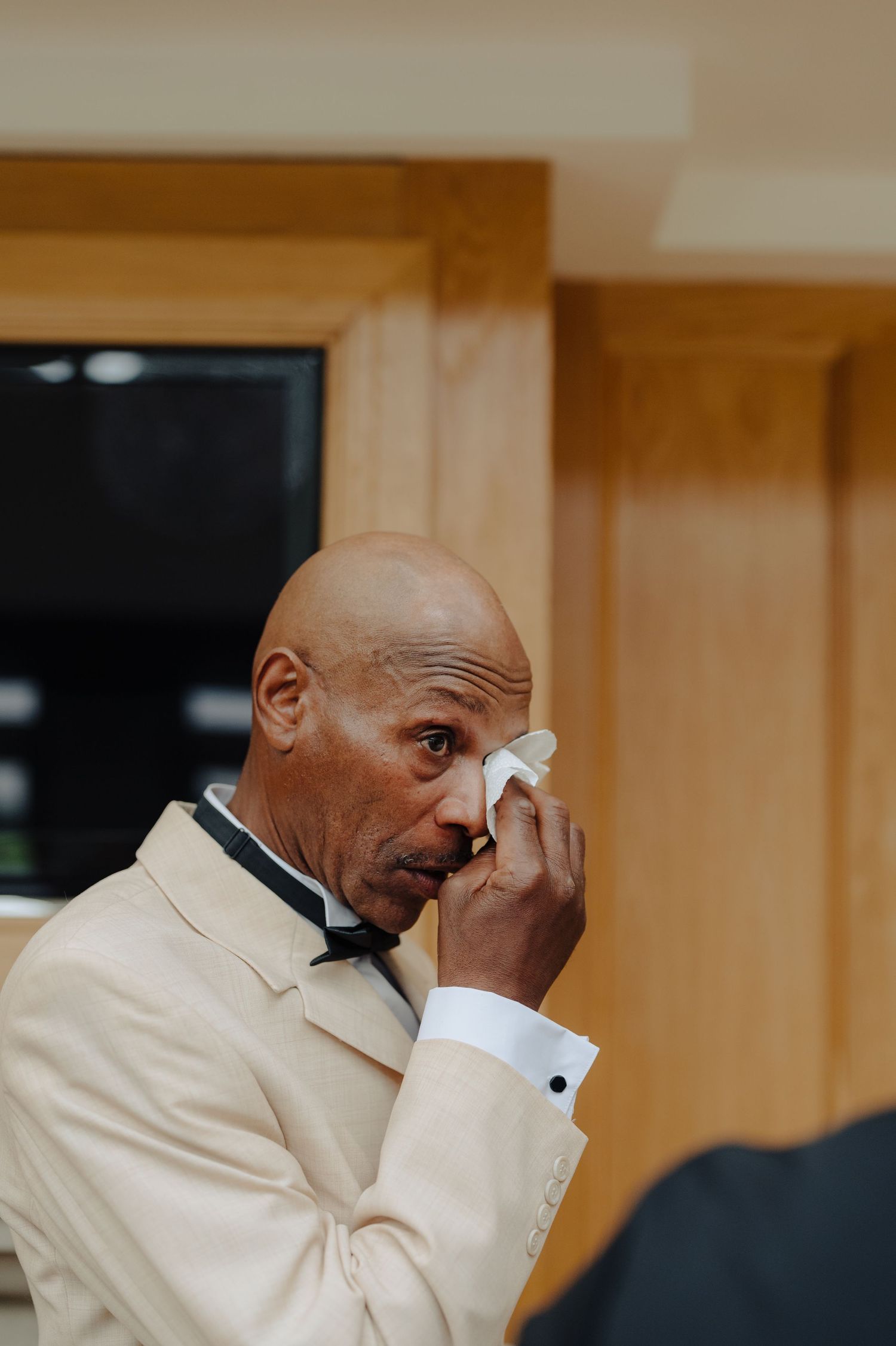 Emotional candid moments captured of someone wiping away tears during a special occasion.