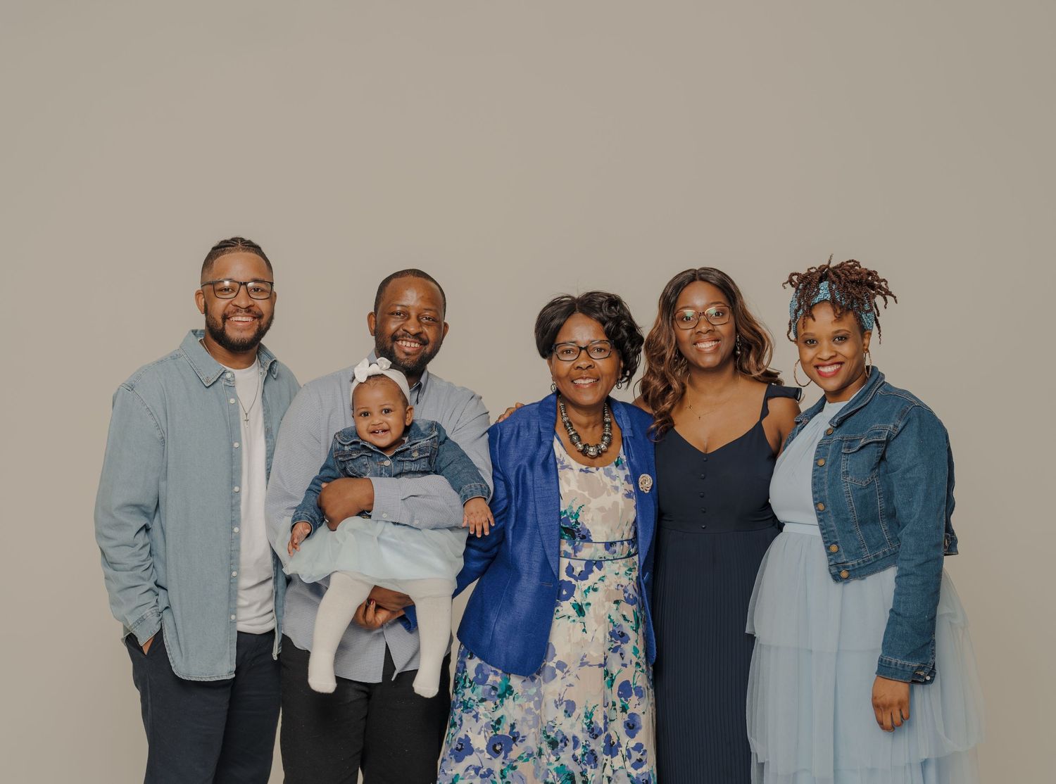 Family portrait session with coordinated blue and denim outfits against neutral backdrop.