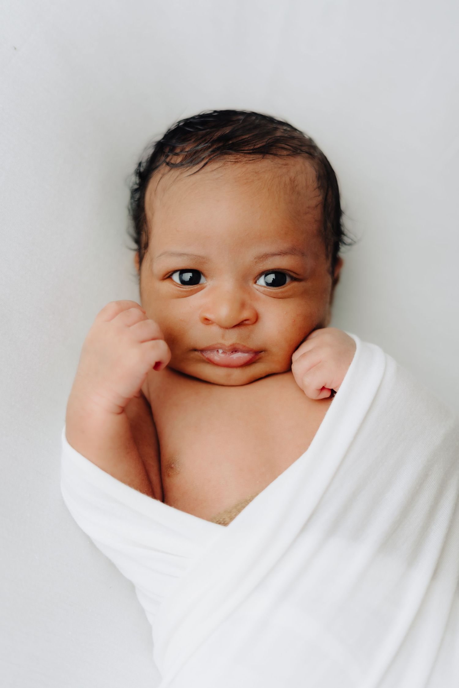 A series of close-up shots showing a smiling baby wrapped in white.