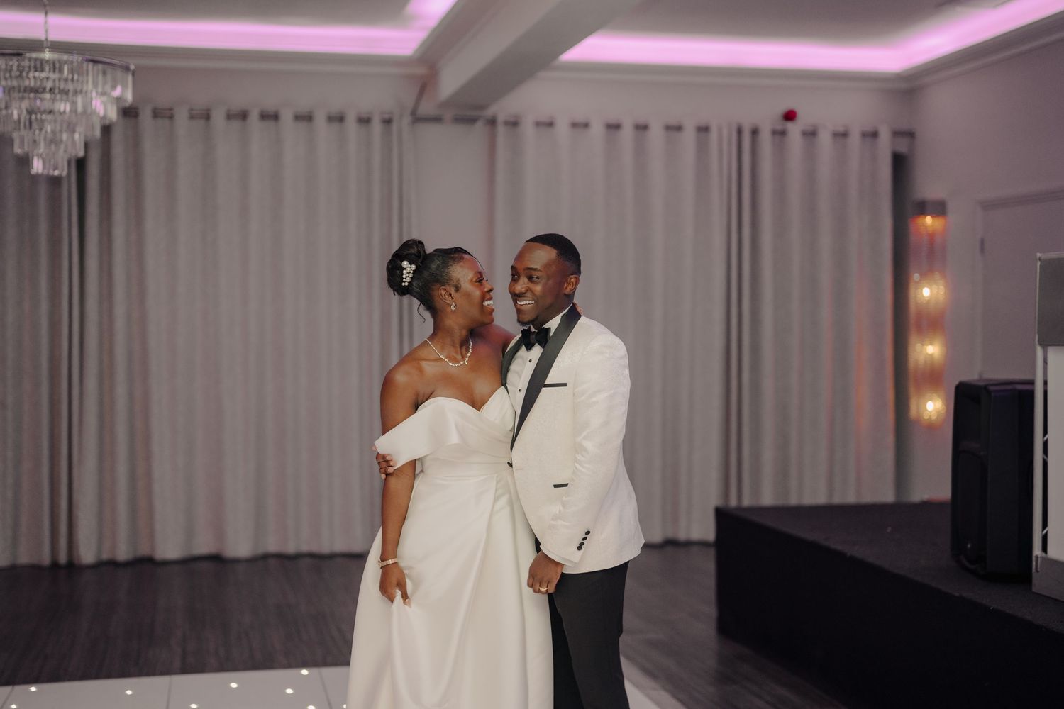 Wedding reception dance floor with purple lighting and elegant white draping.
