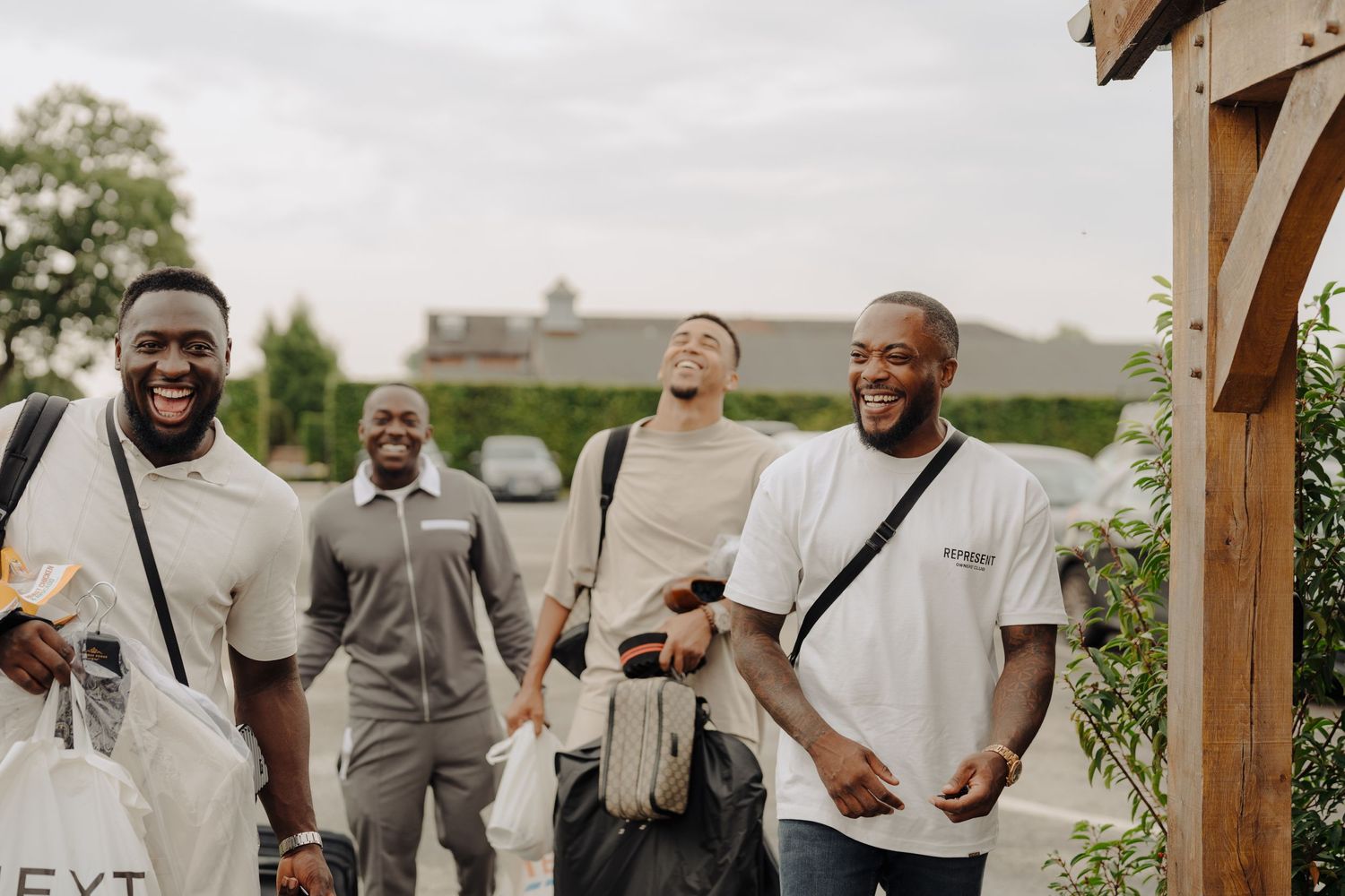 Wedding party members in grey and white attire sharing laughs outdoors.