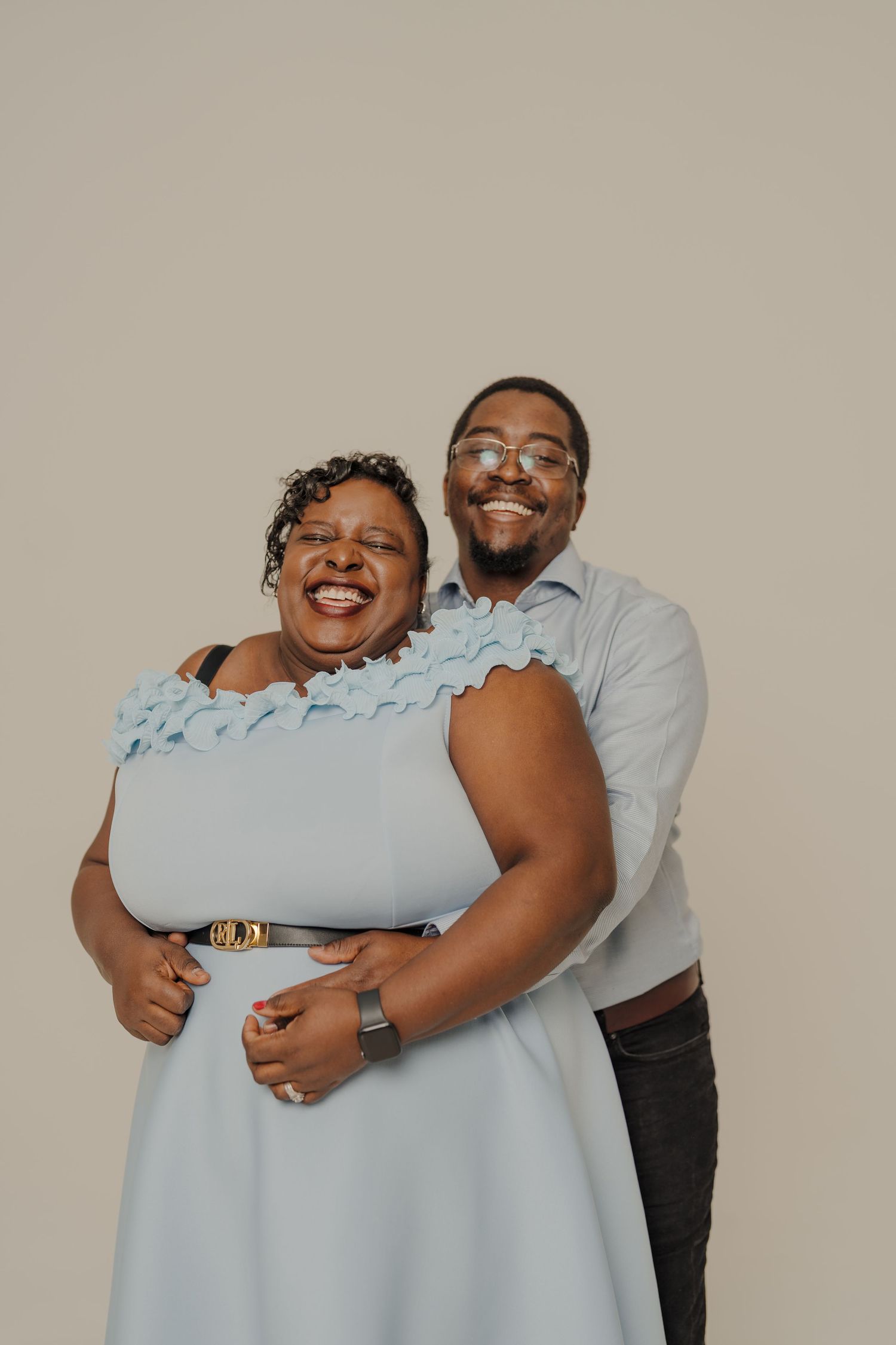Candid portrait session showing joyful laughter and embraces in light blue attire.