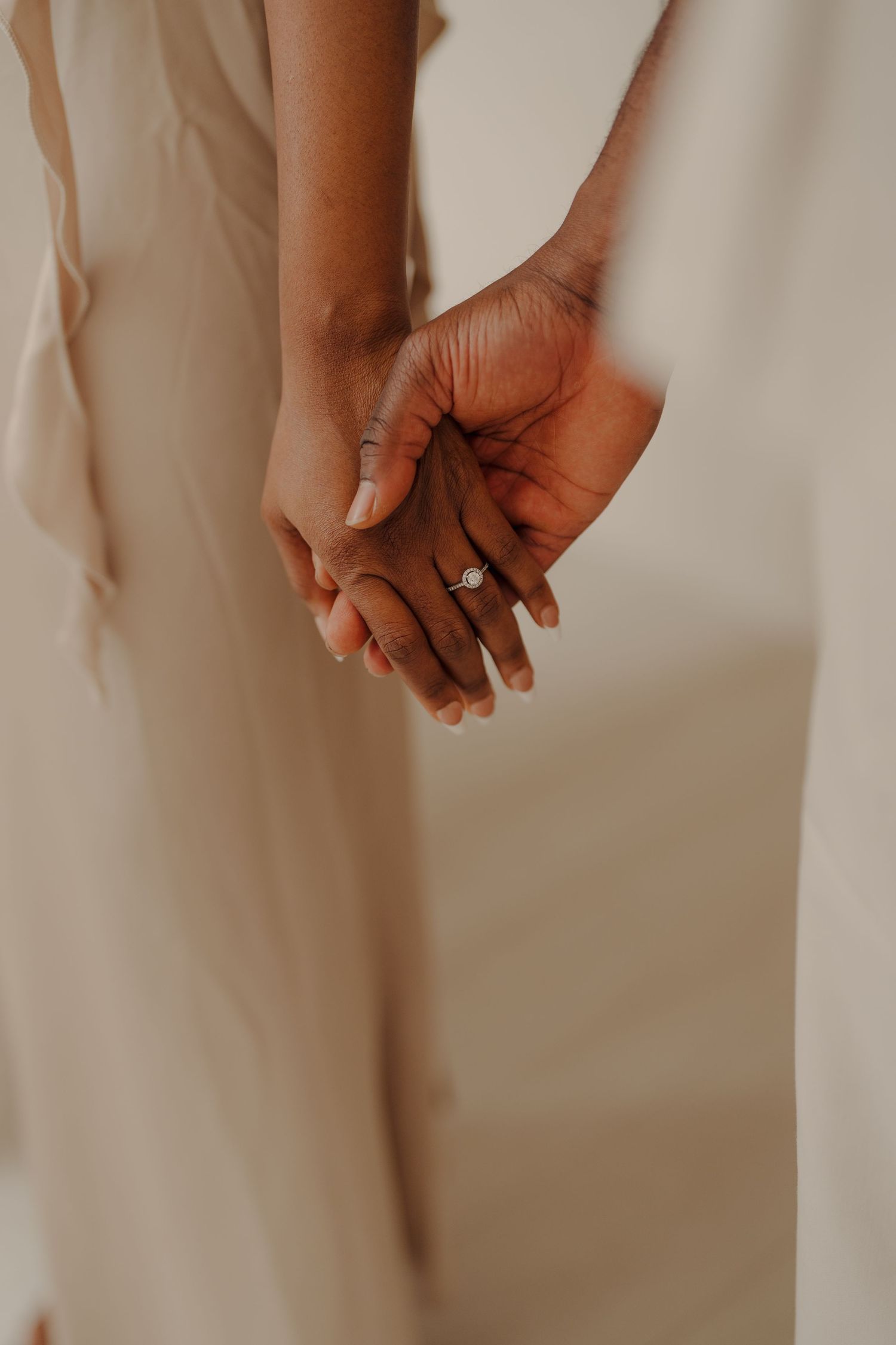 Close-up of hands clasped together against a light neutral background.