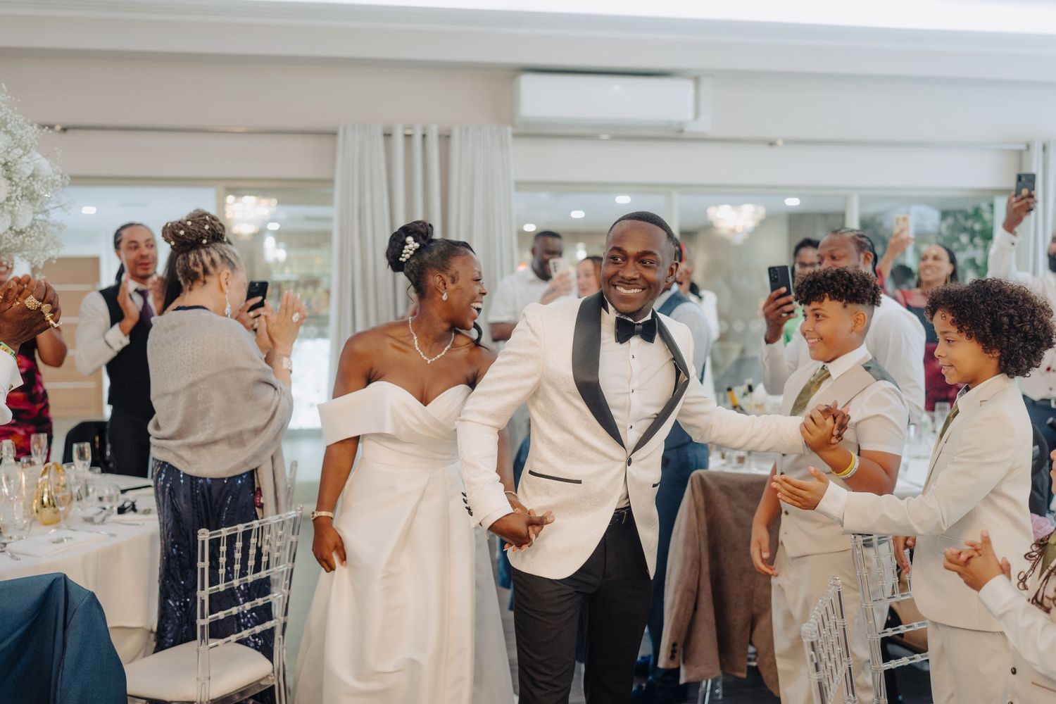 Joyful celebration at wedding reception with guests dancing and mingling.