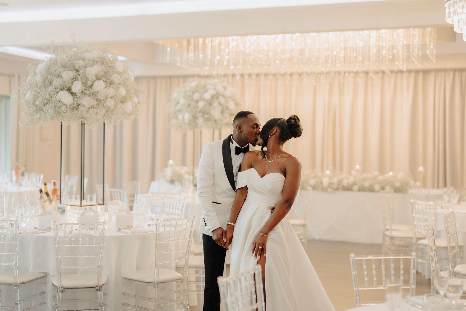 Elegant wedding venue decorated with white floral arrangements and chandeliers for reception.