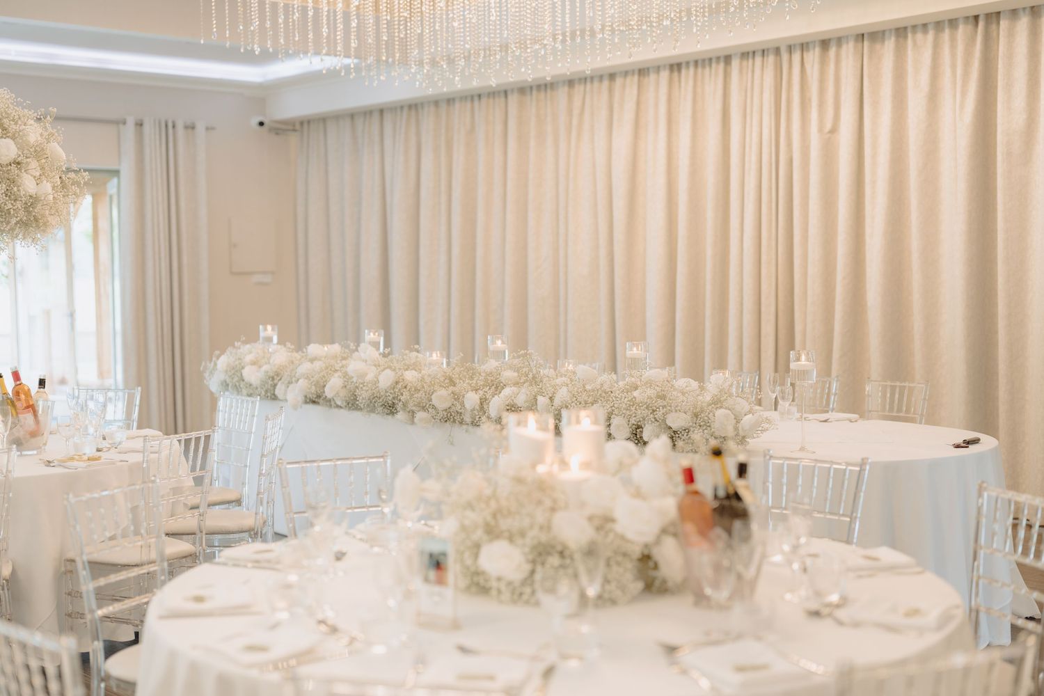 Elegant wedding reception venue with white floral centerpieces and draped fabric ceiling decorations.