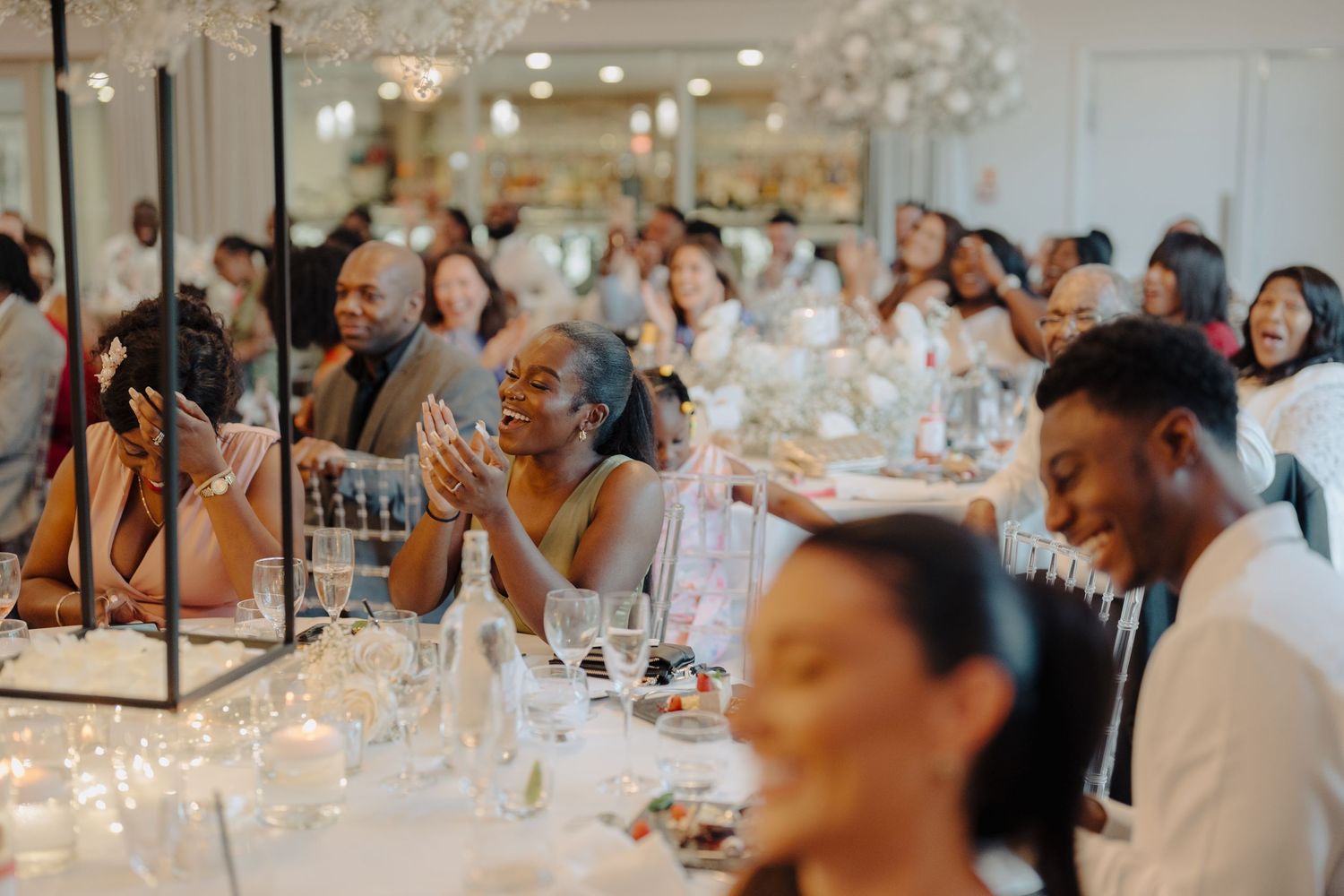 Wedding reception guests enjoying dinner and conversation at tables with elegant decor.
