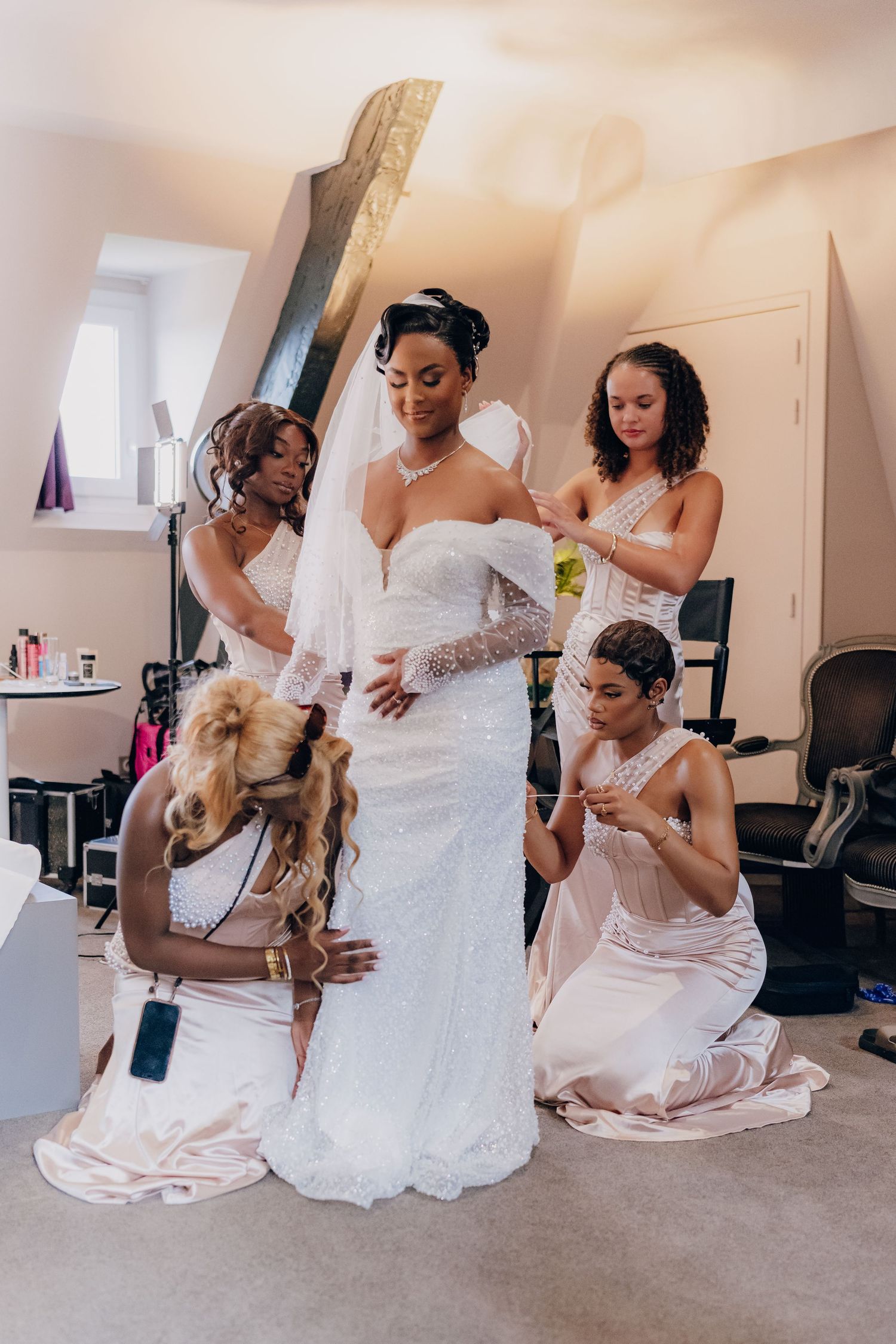 A wedding party gets ready in a series of candid moments showing dress adjustments and preparations in white gowns.