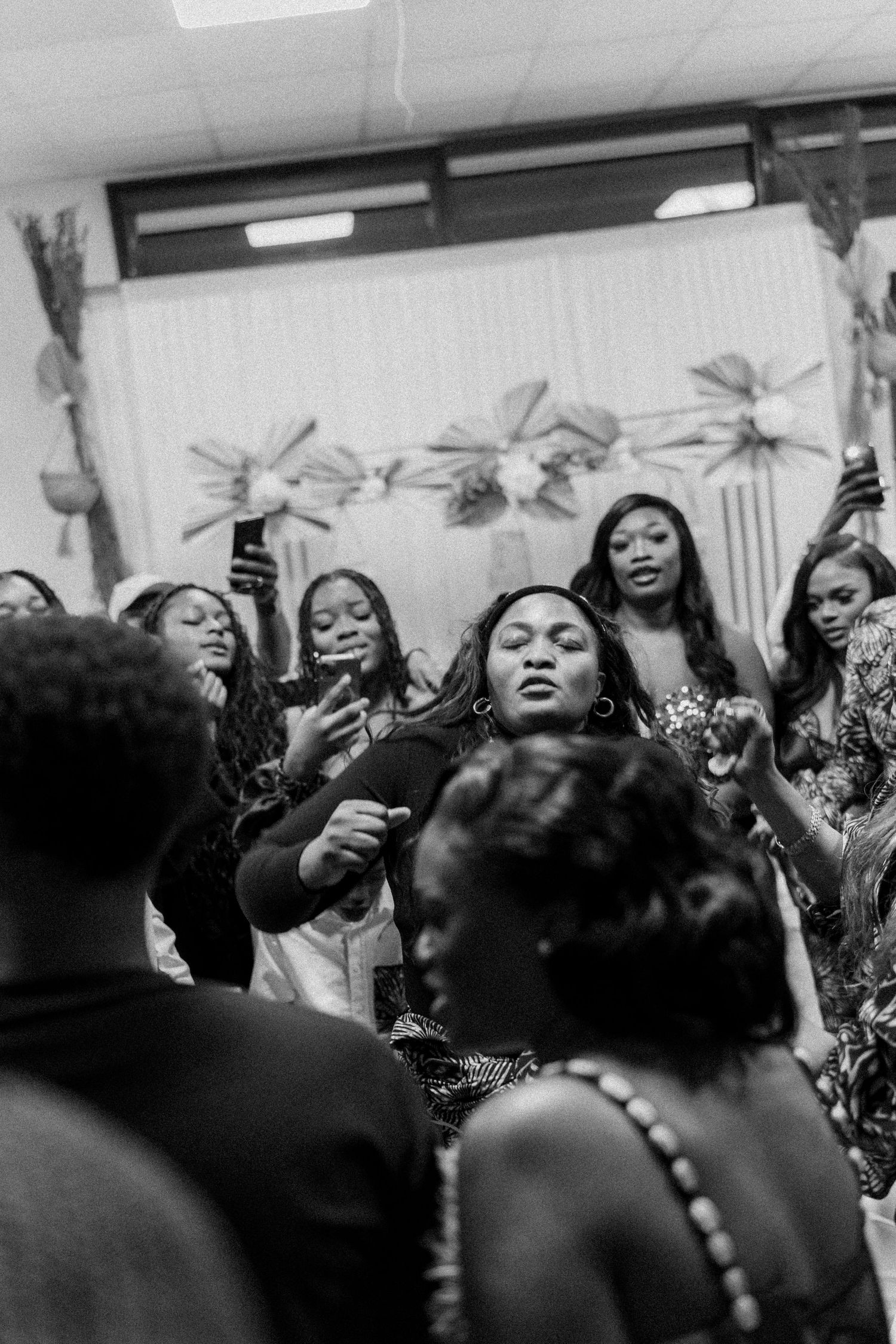 Group of people raising phones at celebratory event in black and white.