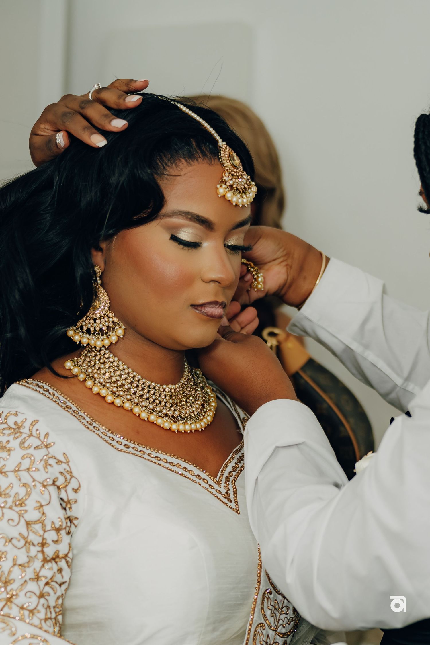 Traditional Indian bridal jewelry and white embroidered dress showcased in intimate wedding preparation moment.