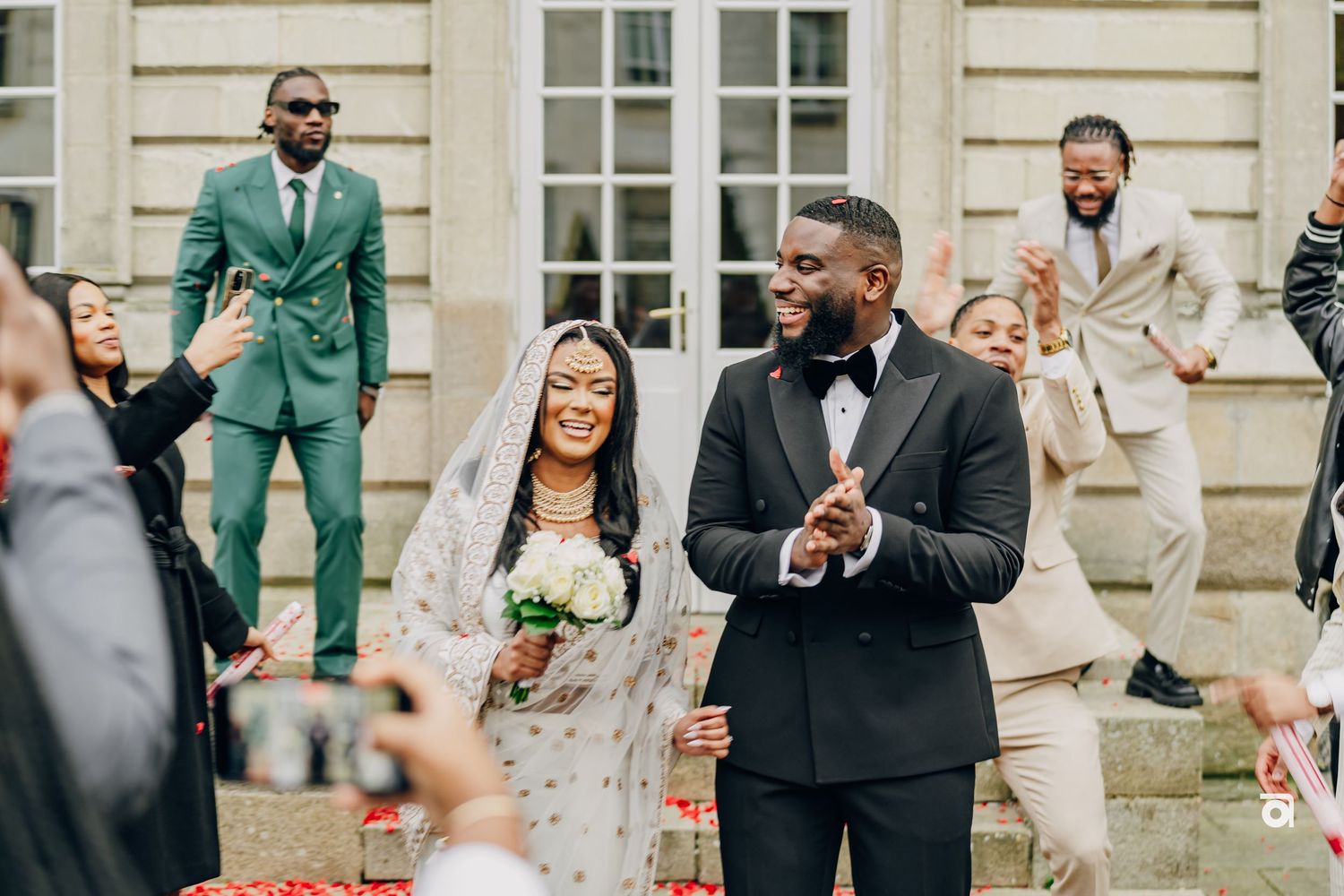 Wedding celebration on elegant stone steps with couple in formal attire.
