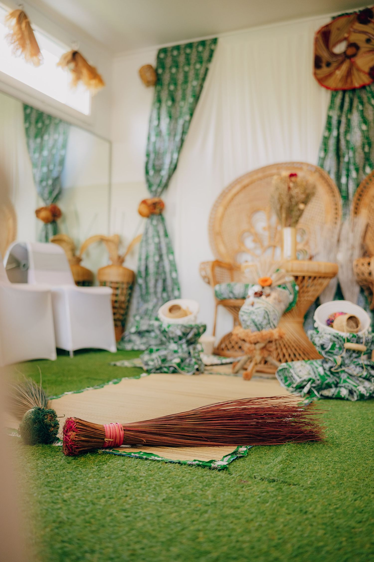 Traditional wedding decorations laid out on green carpet including woven baskets and ceremonial items.