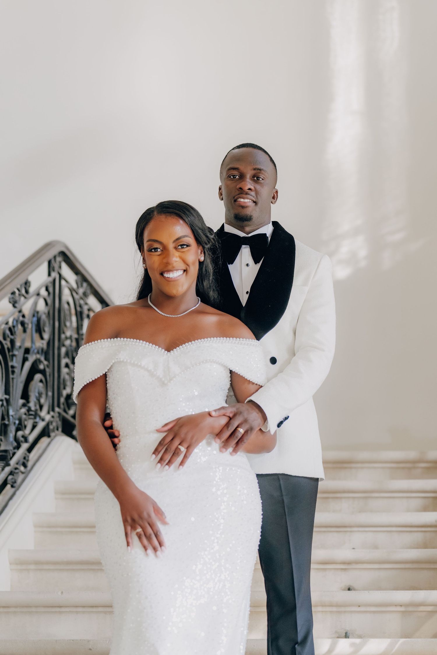 Elegant indoor wedding portraits on grand staircase with ornate iron railings.