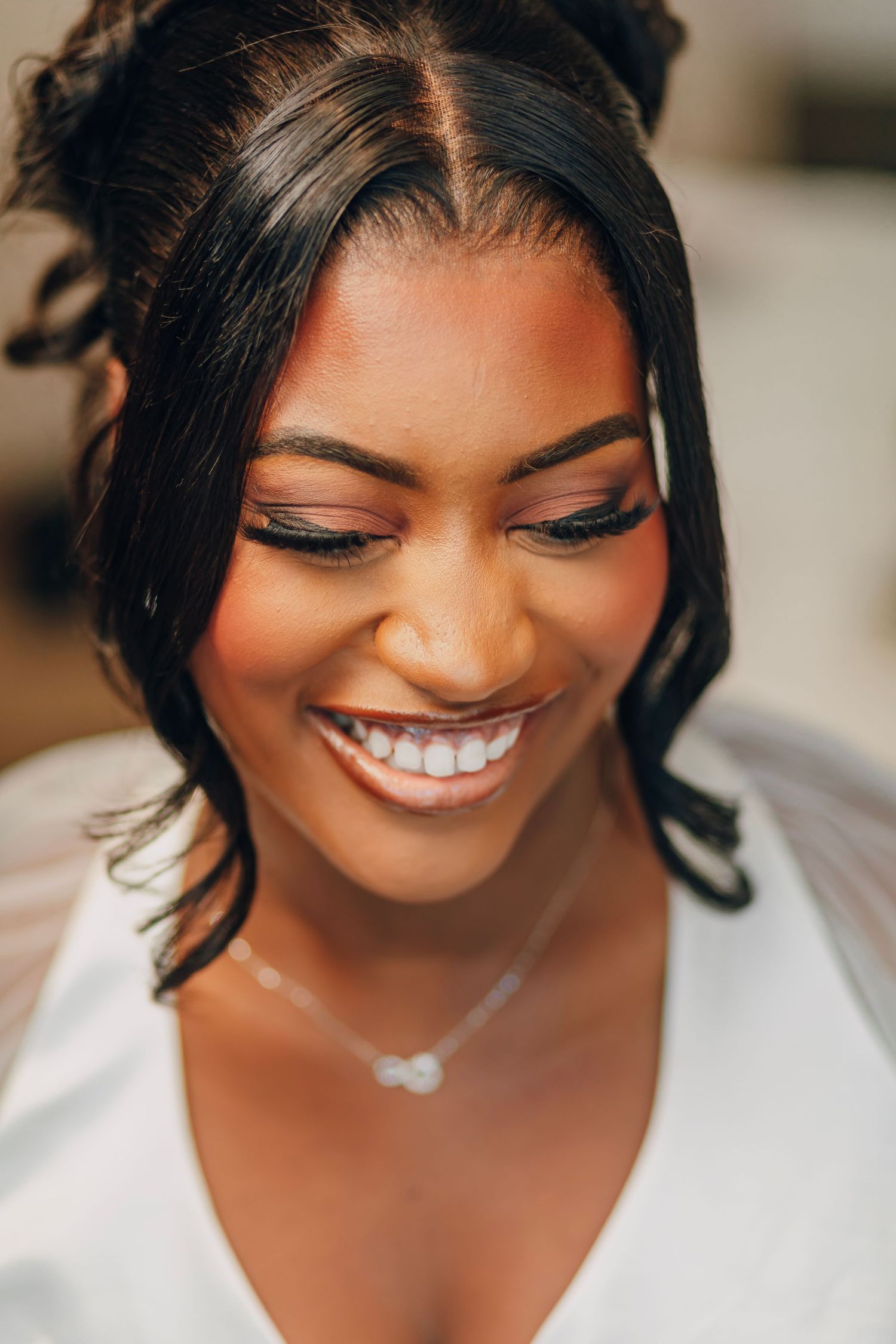 Candid bridal beauty shot featuring radiant smile and delicate necklace.