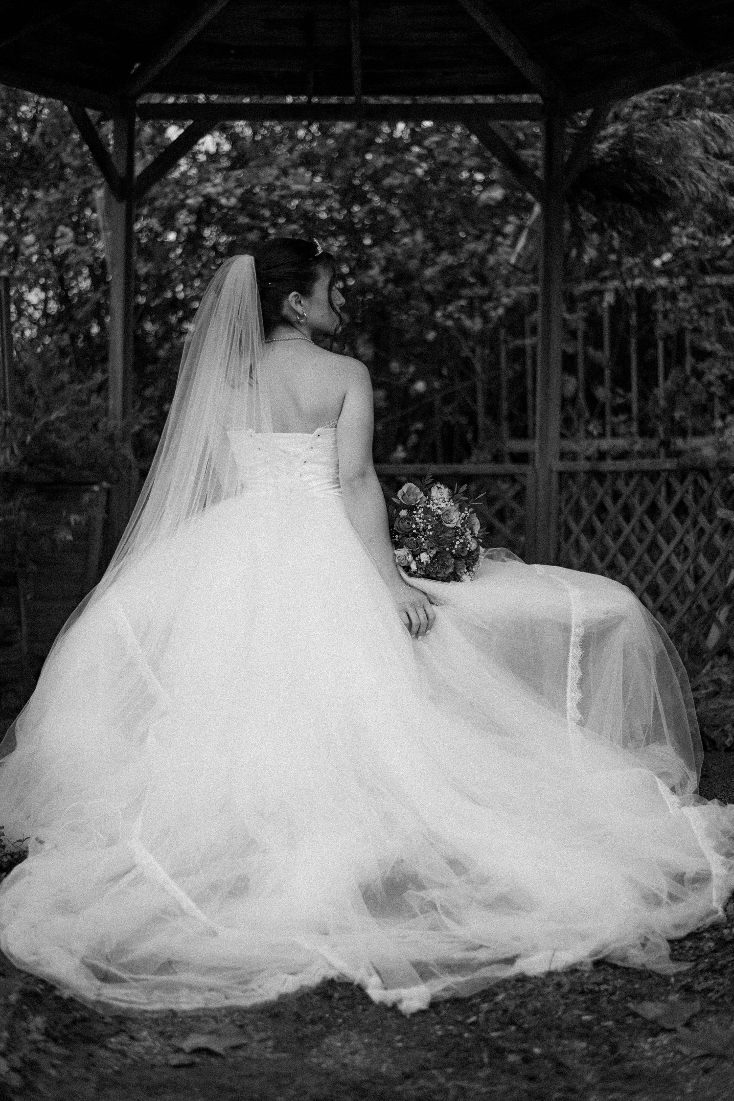A flowing white wedding dress with tulle skirt is artfully arranged in a series of black and white photographs.