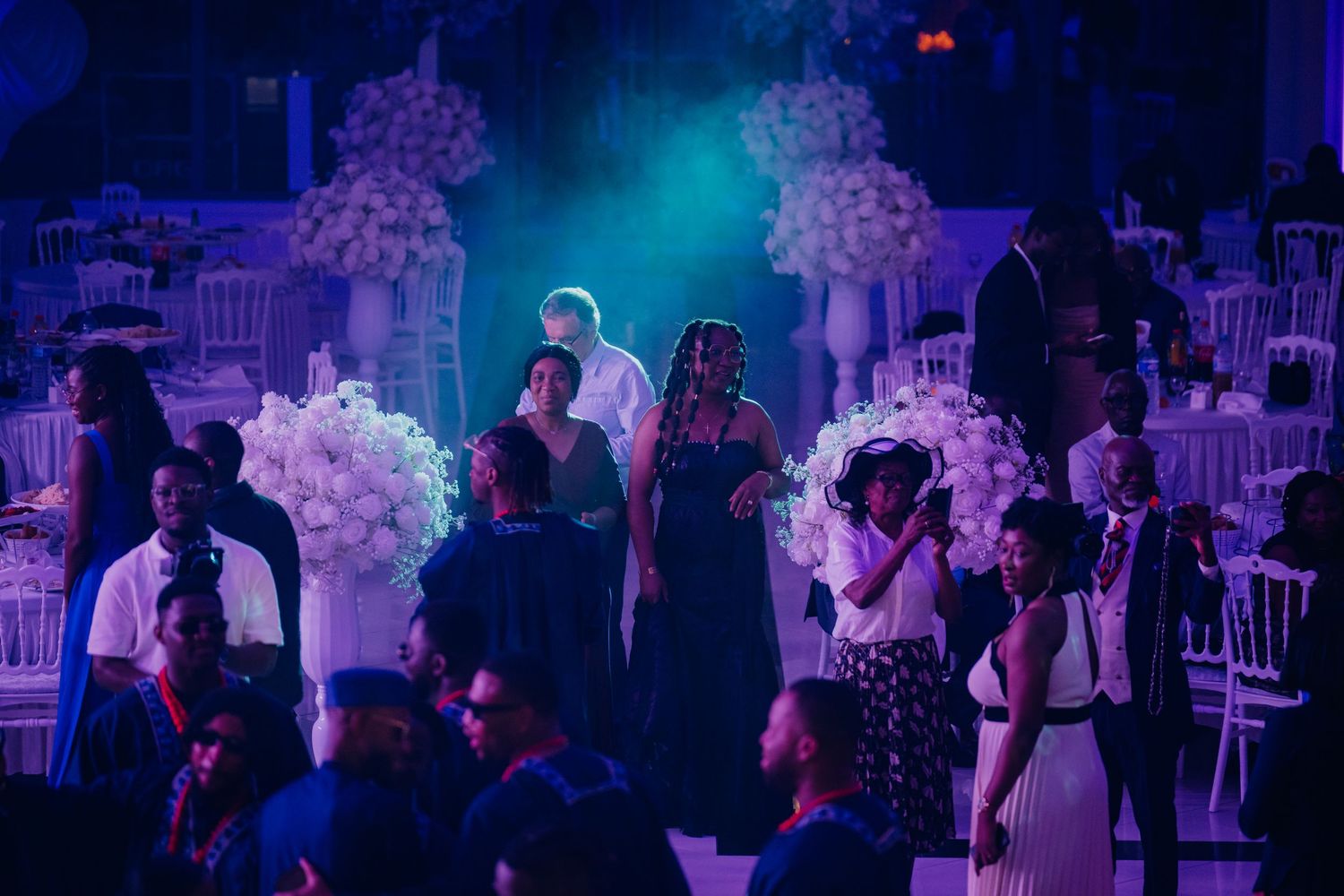 Guests dancing and celebrating at an evening wedding reception with blue and purple ambient lighting.